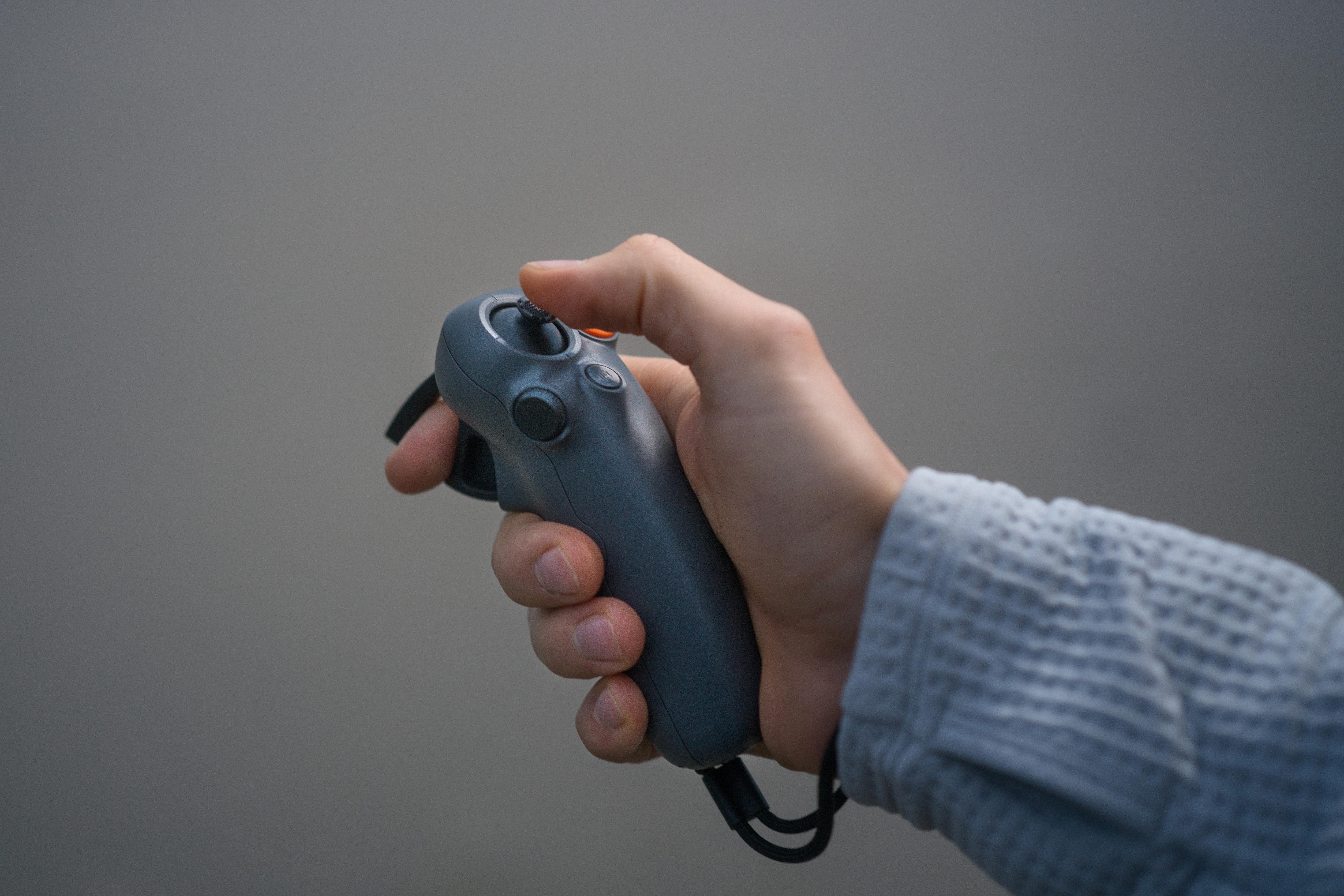 Eine Hand, die einen grauen Virtual-Reality-Controller hält.