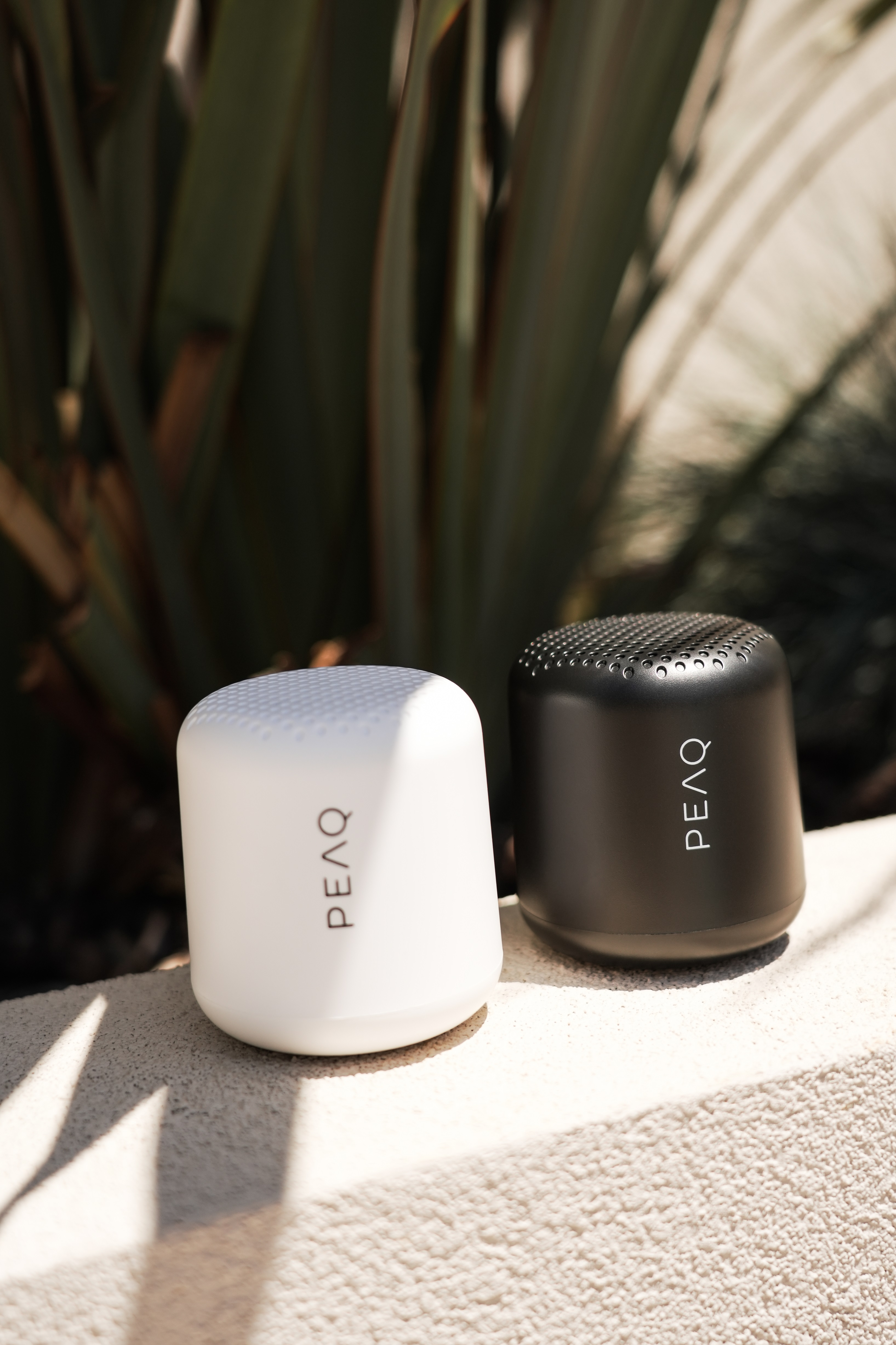 Dwa małe białe i czarne głośniki PEAQ, na zewnątrz, zbliżenie.