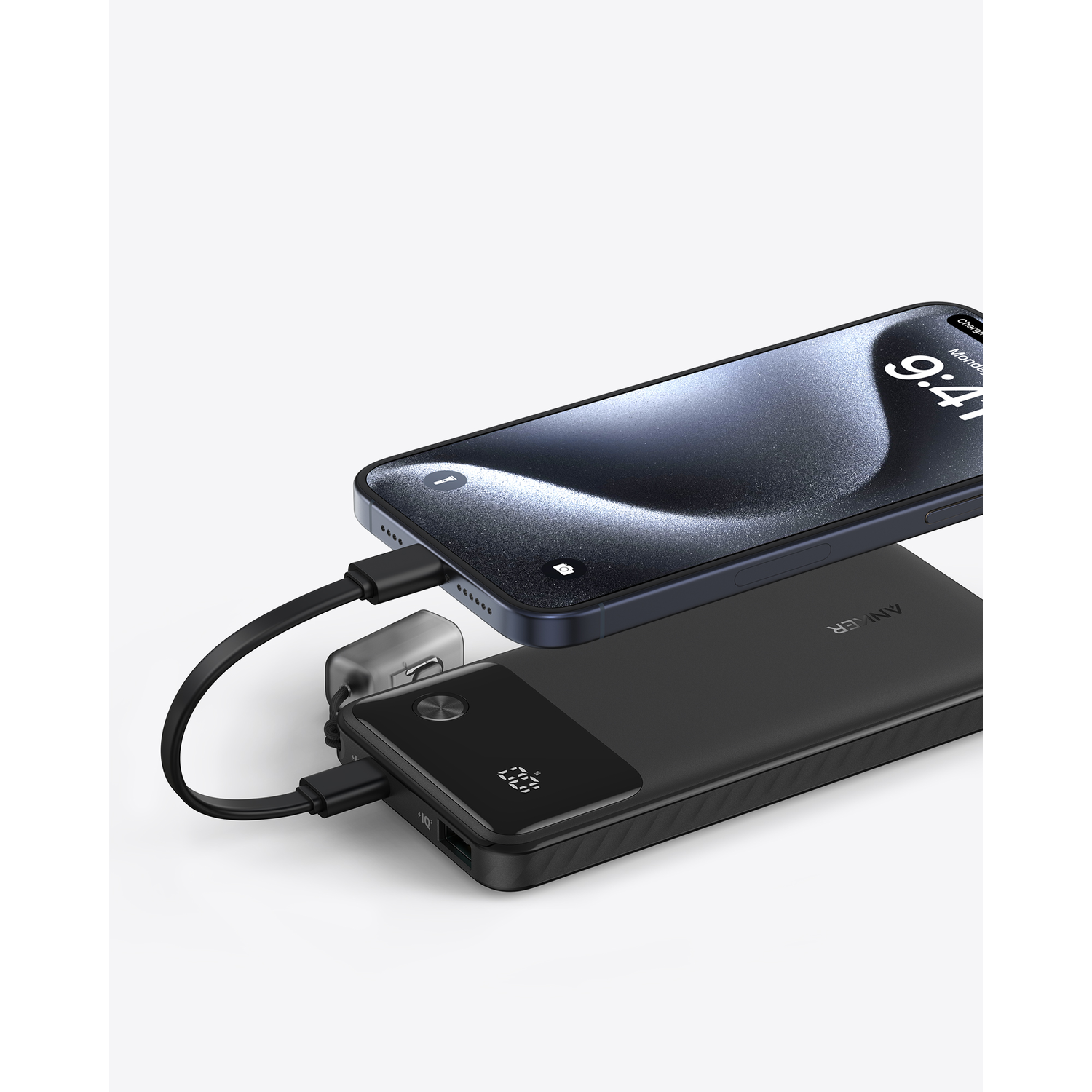 Zwarte powerbank die een telefoon oplaadt op een wit oppervlak.
