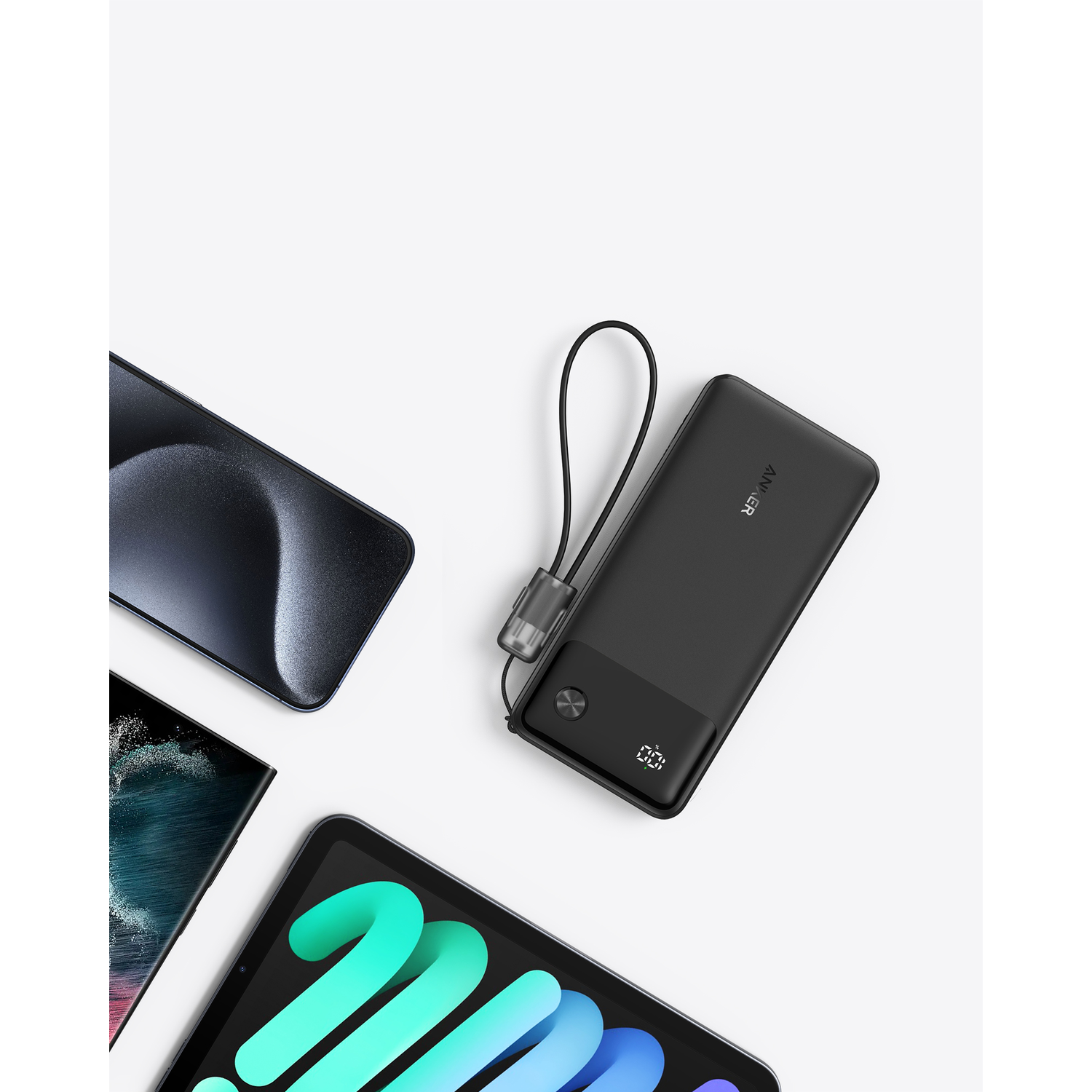 Een zwarte powerbank met een oplaadkabel, telefoon en tablet.