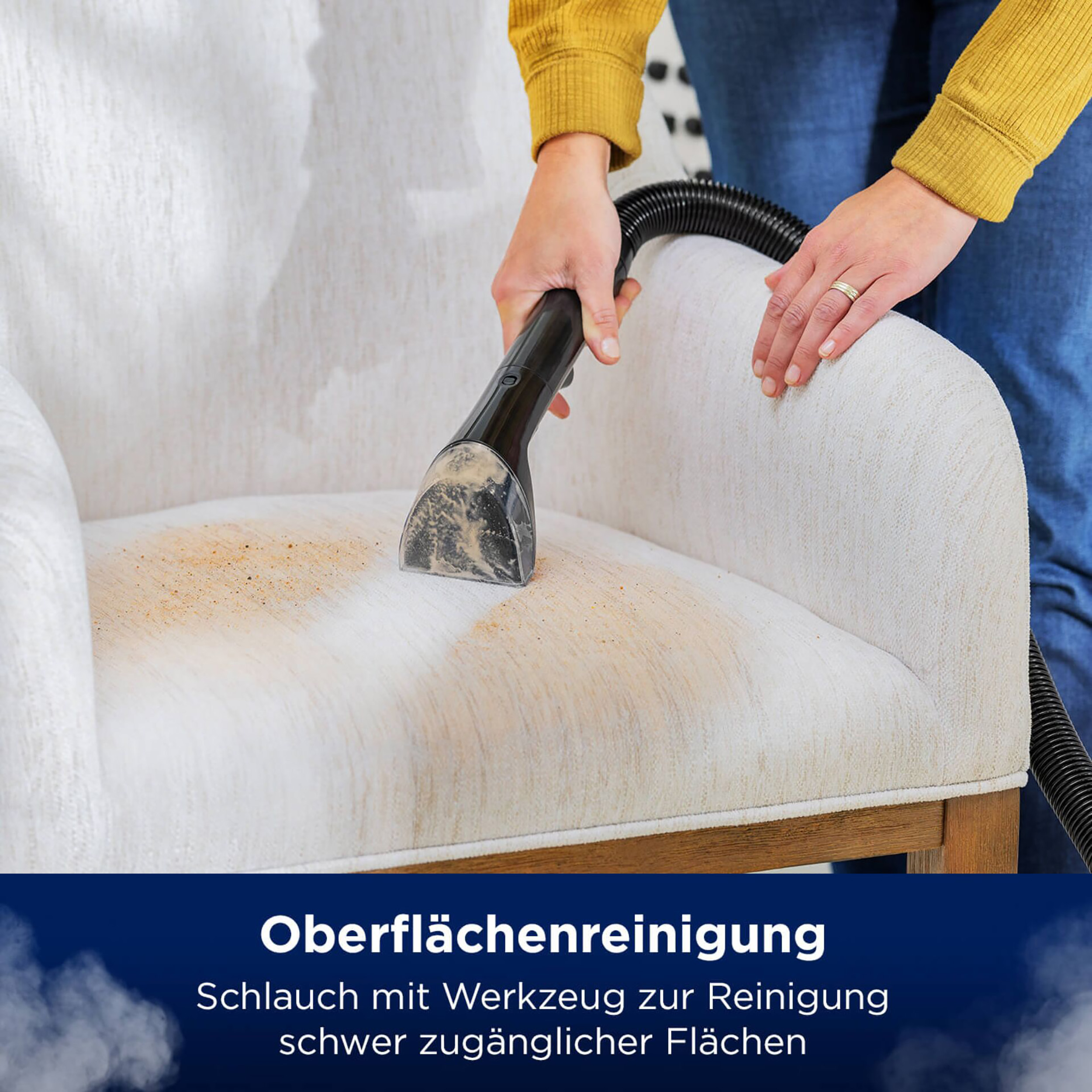 Person reinigt Stuhl mit schwarzem Reinigungswerkzeug. Der Stuhl hat Flecken.