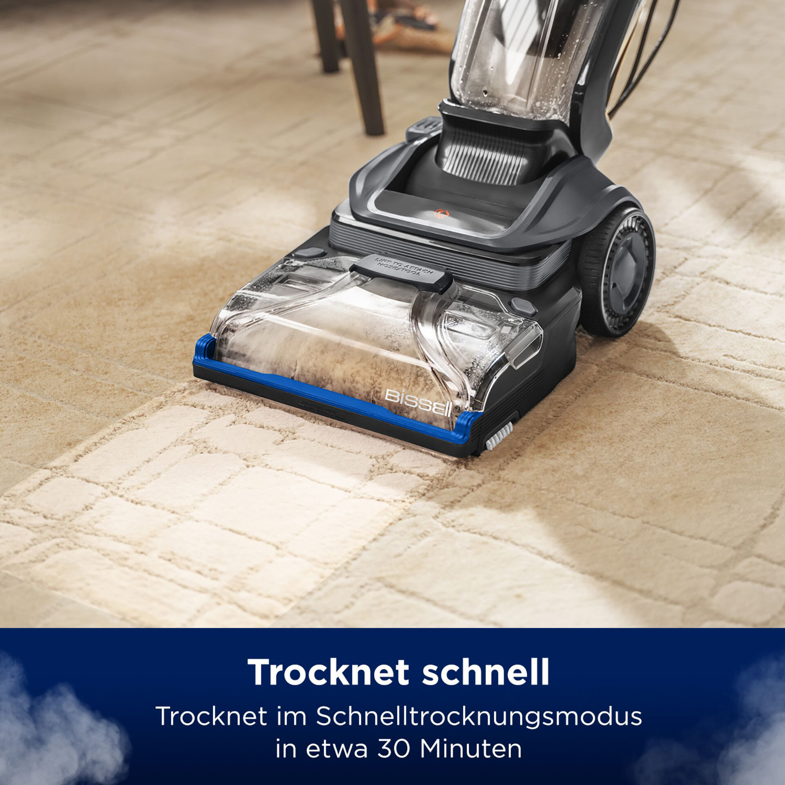 Staubsauger auf einem Teppich. Ein blauer Streifen am Staubsaugerkopf. Text unten.