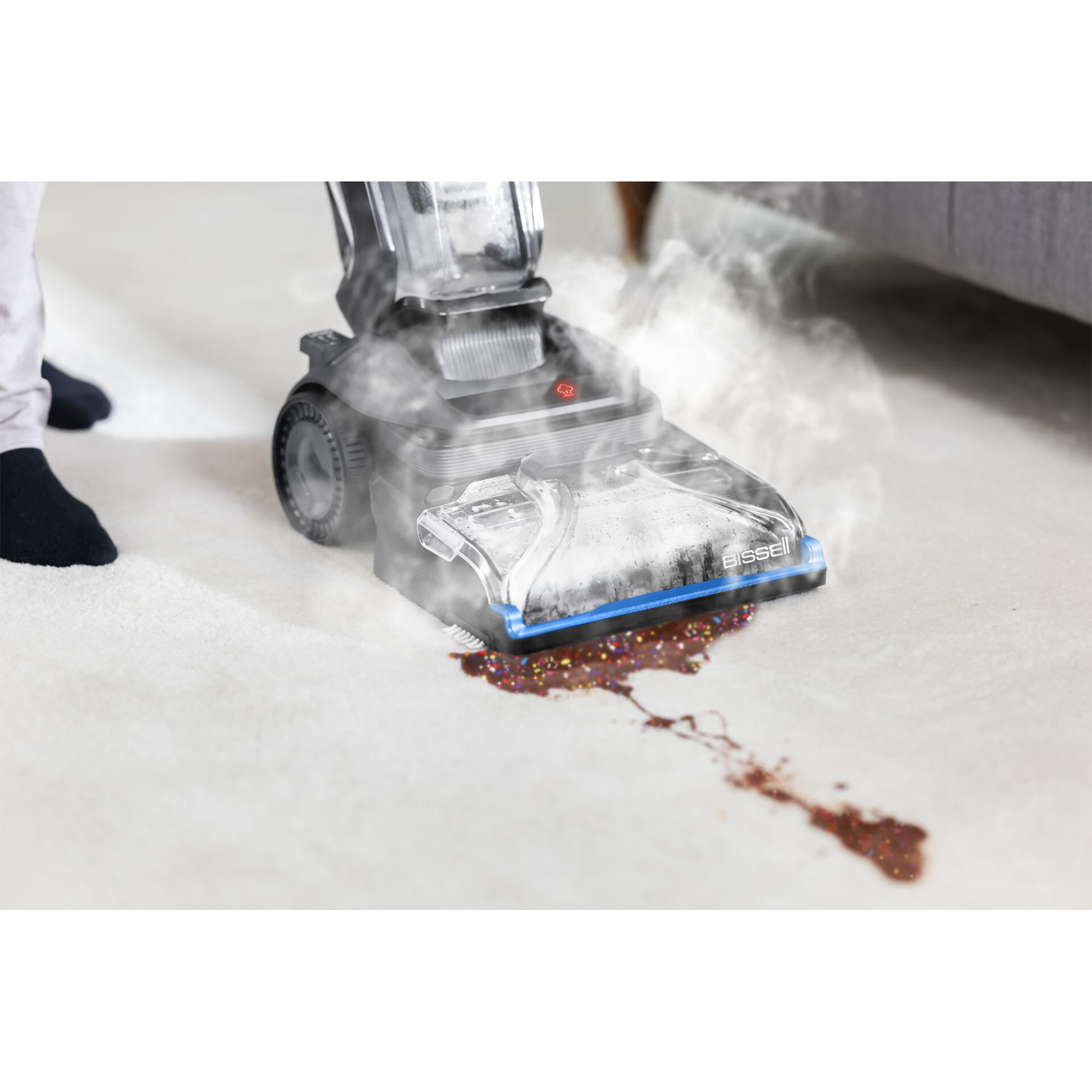 Ein Dampfreiniger entfernt einen Fleck auf einem weißen Teppich, Füße einer Person sichtbar.