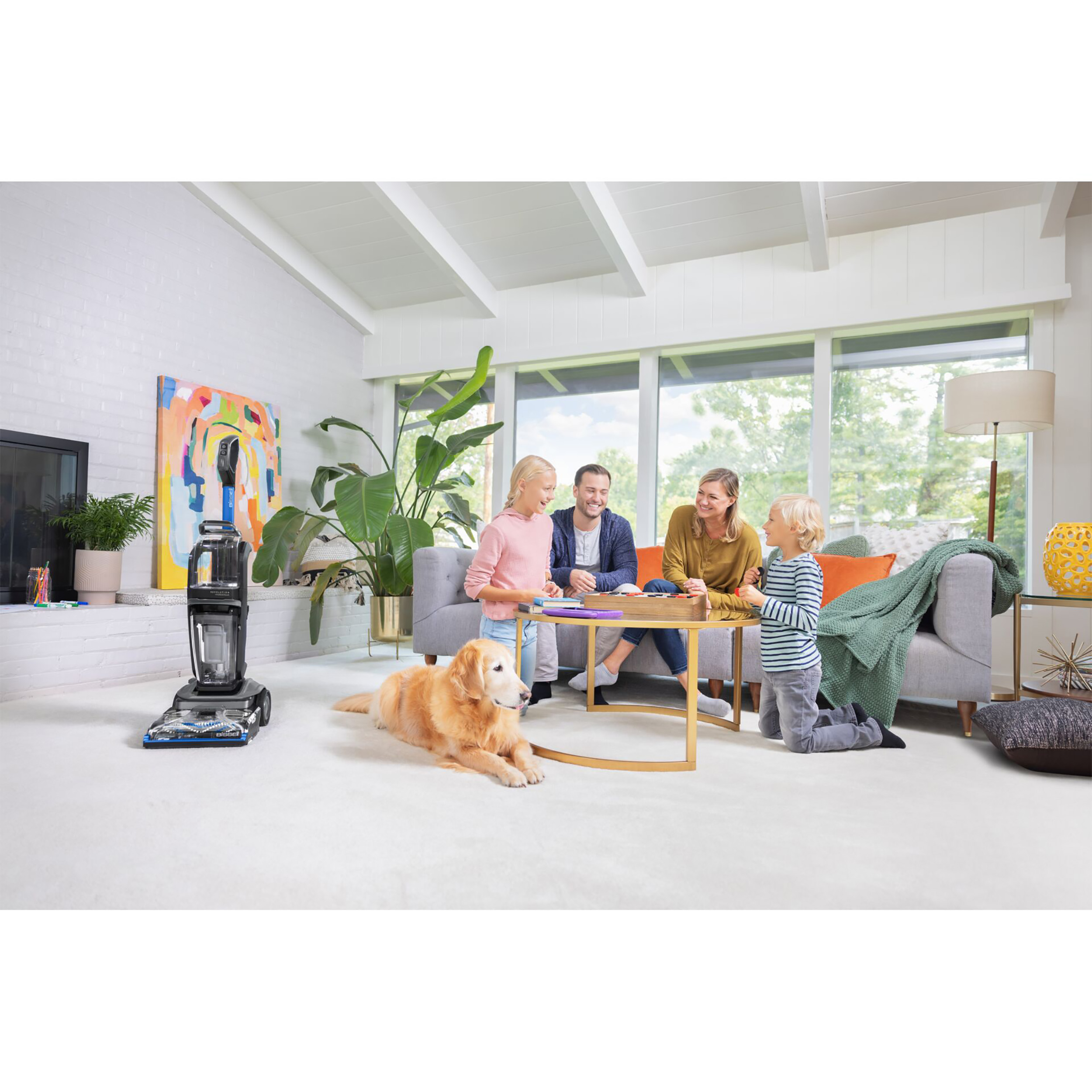 Wohnzimmer mit einer Familie. Es gibt einen Hund, einen Staubsauger und ein Gemälde an der Wand.