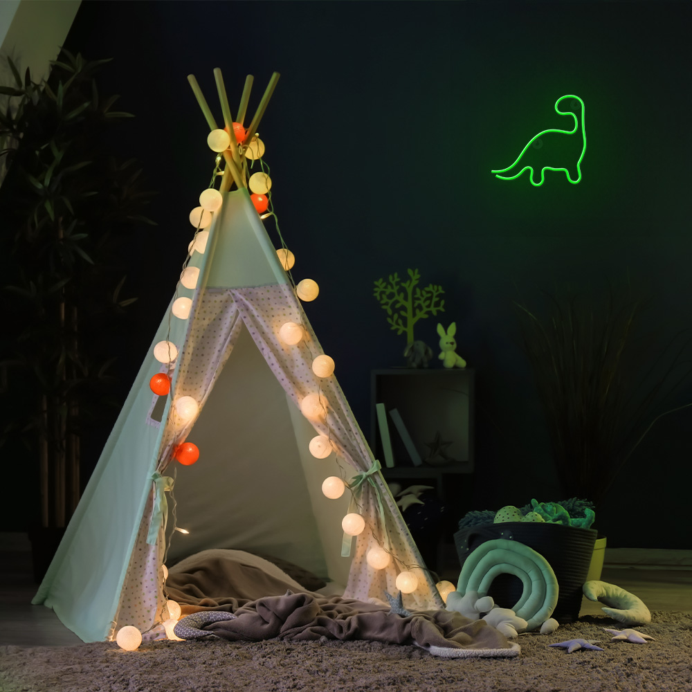 Egy díszített tipi sátor neon dinoszaurusz táblával, tündérfényekkel és játékokkal.
