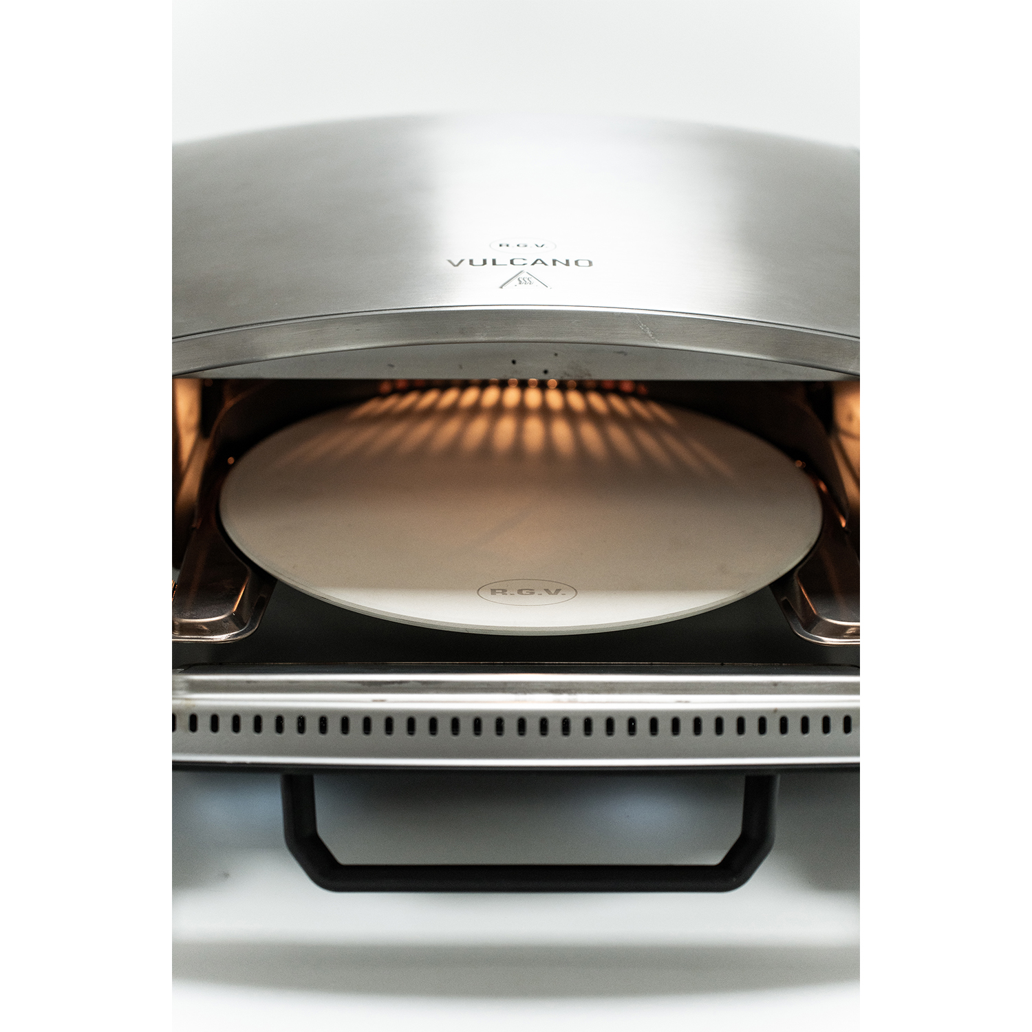 Interno di un forno per pizza con pietra per pizza. La luce calda brilla dall'interno.