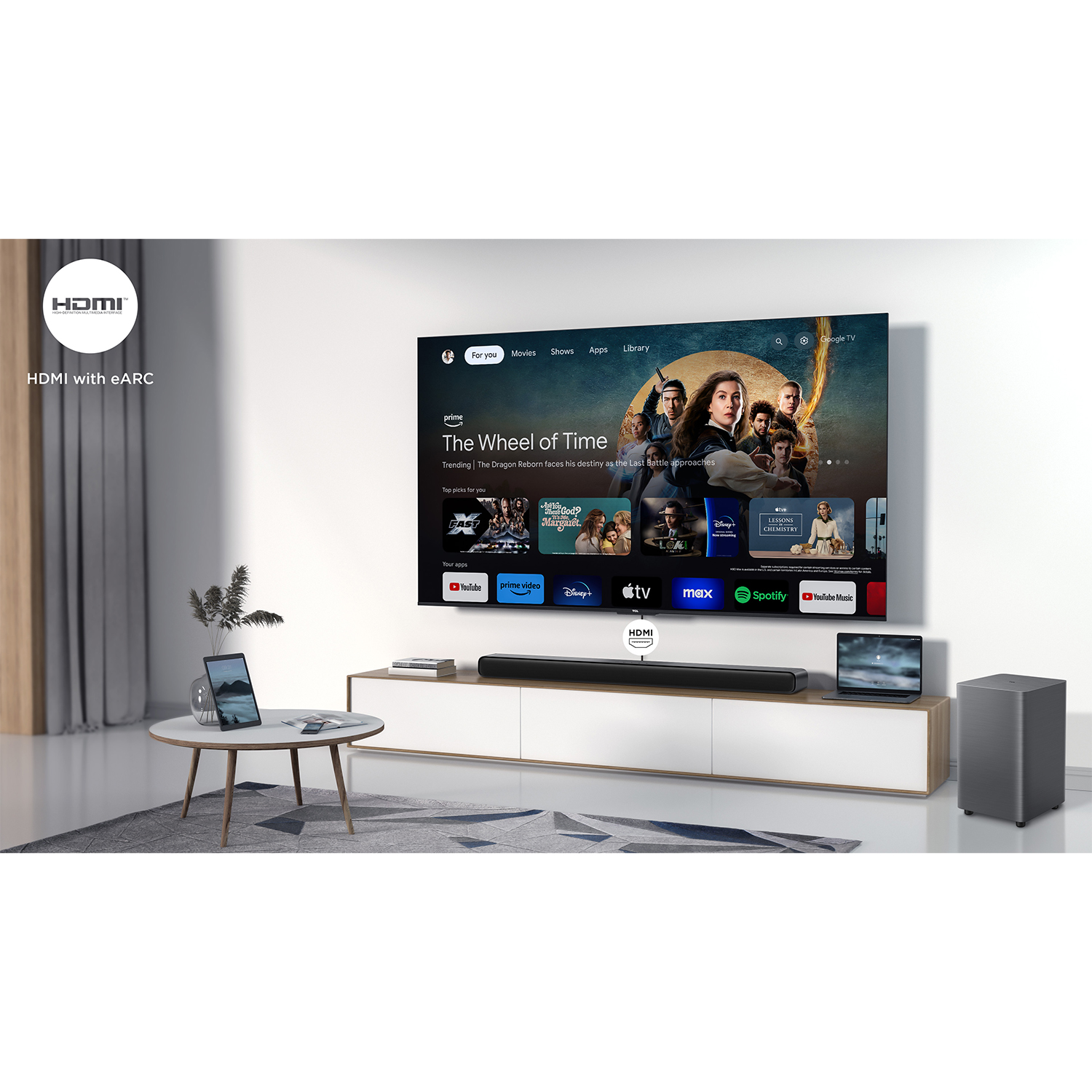 Lo schermo TV mostra uno spettacolo, soundbar sotto, due dispositivi ai lati, in una stanza.