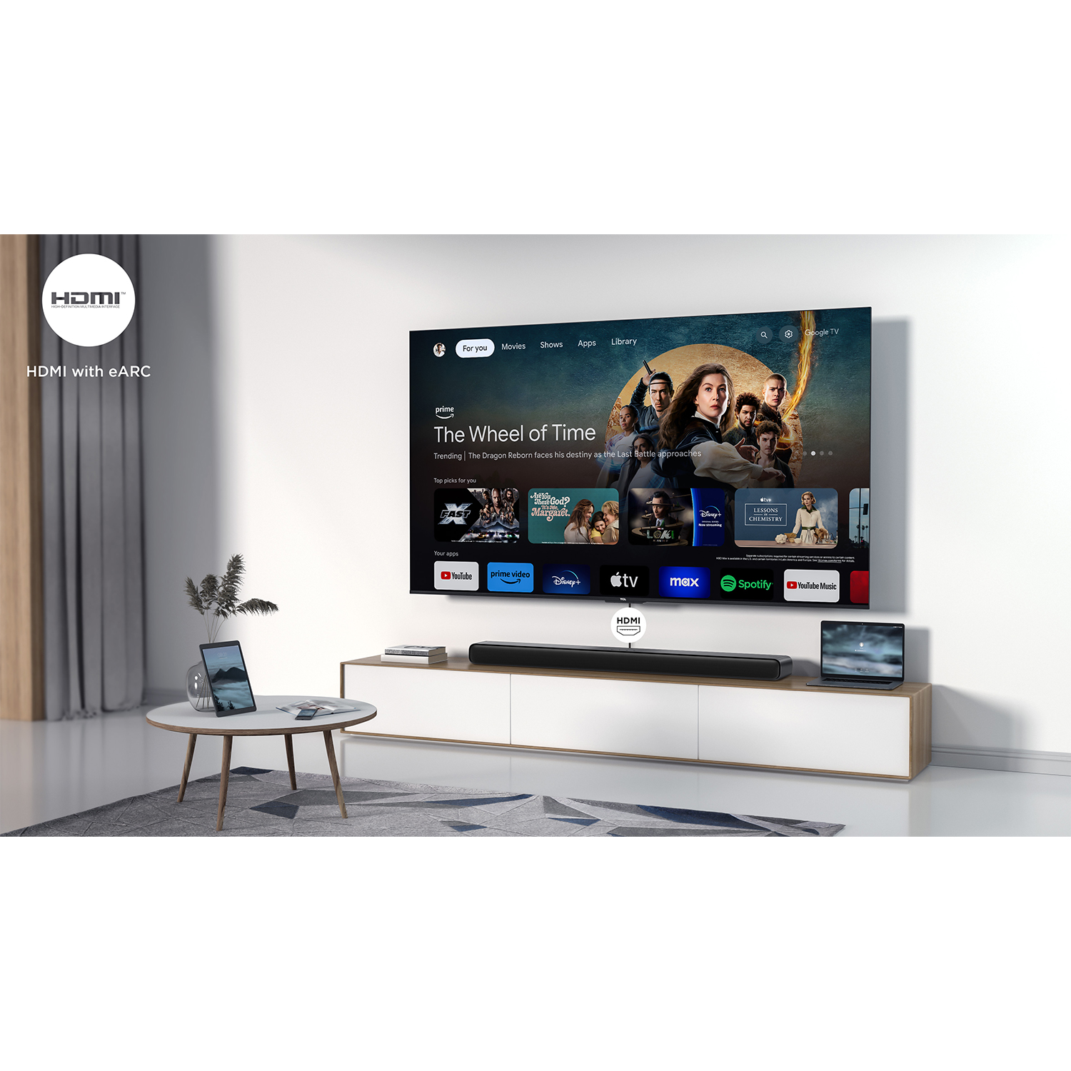 TV con servizio streaming, soundbar e tavolo con laptop. Parete bianca e tende.