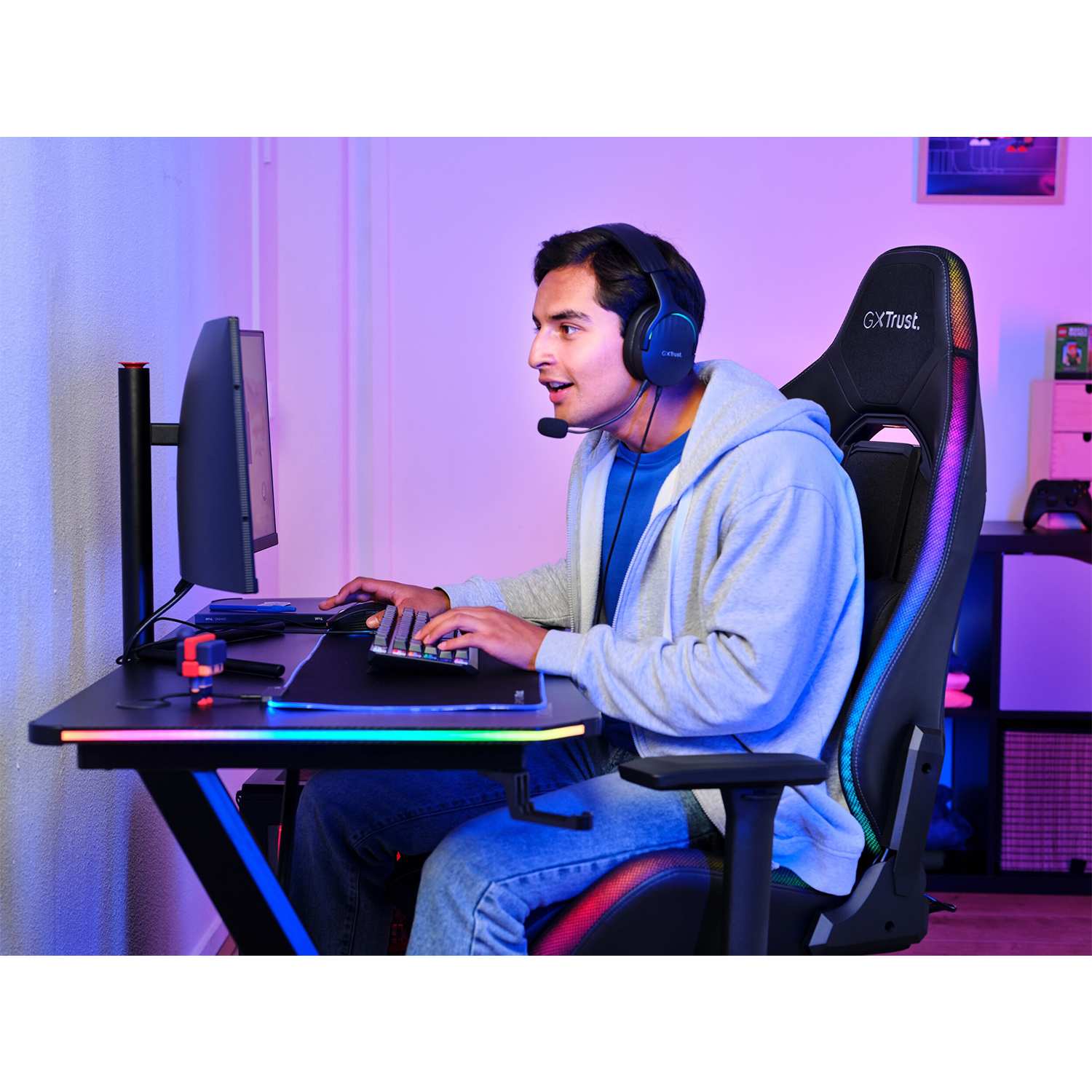 Un uomo con le cuffie gioca al computer seduto su una sedia da gaming.