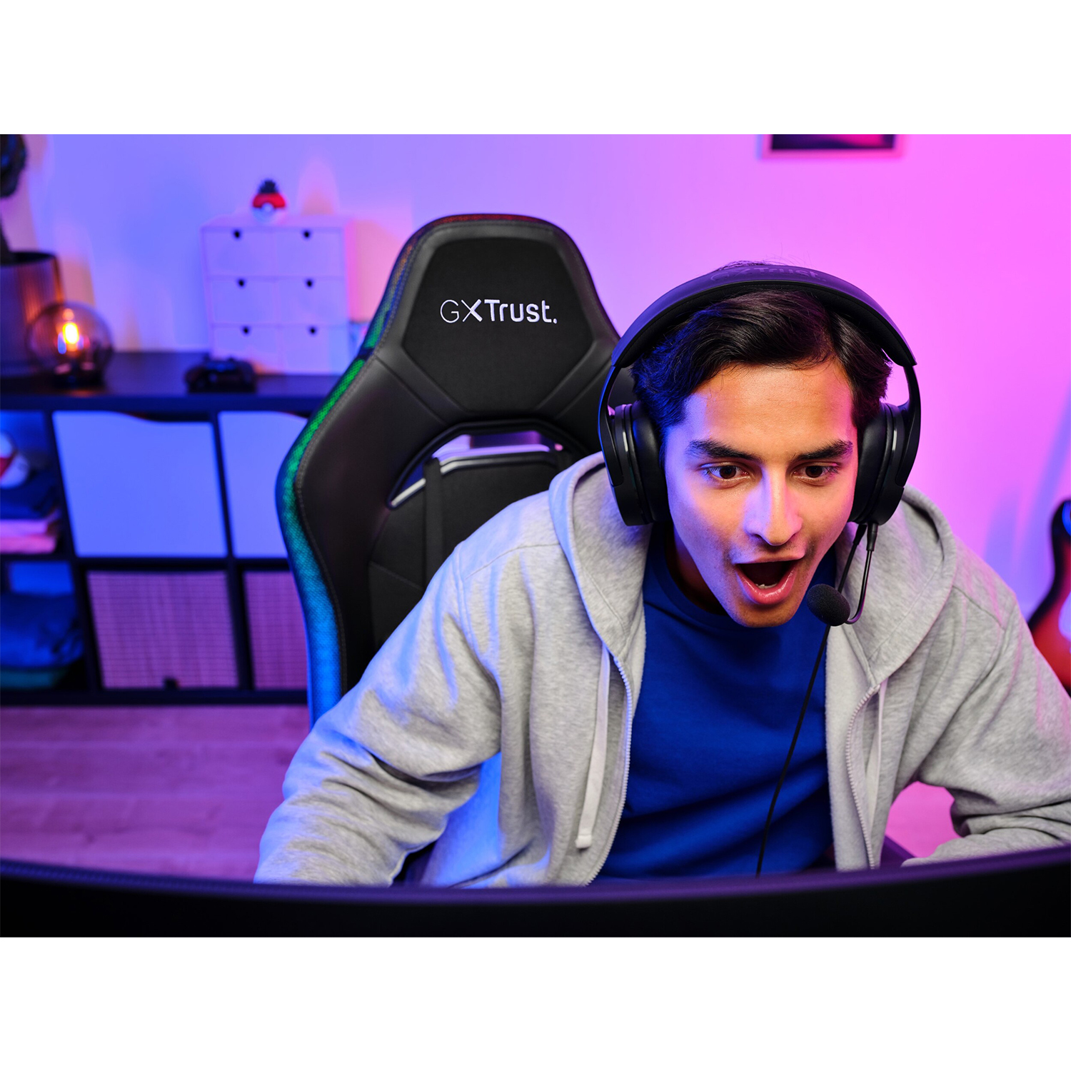 Uomo con cuffie che gioca, sorpreso. Sedia e schermo da gioco sullo sfondo.