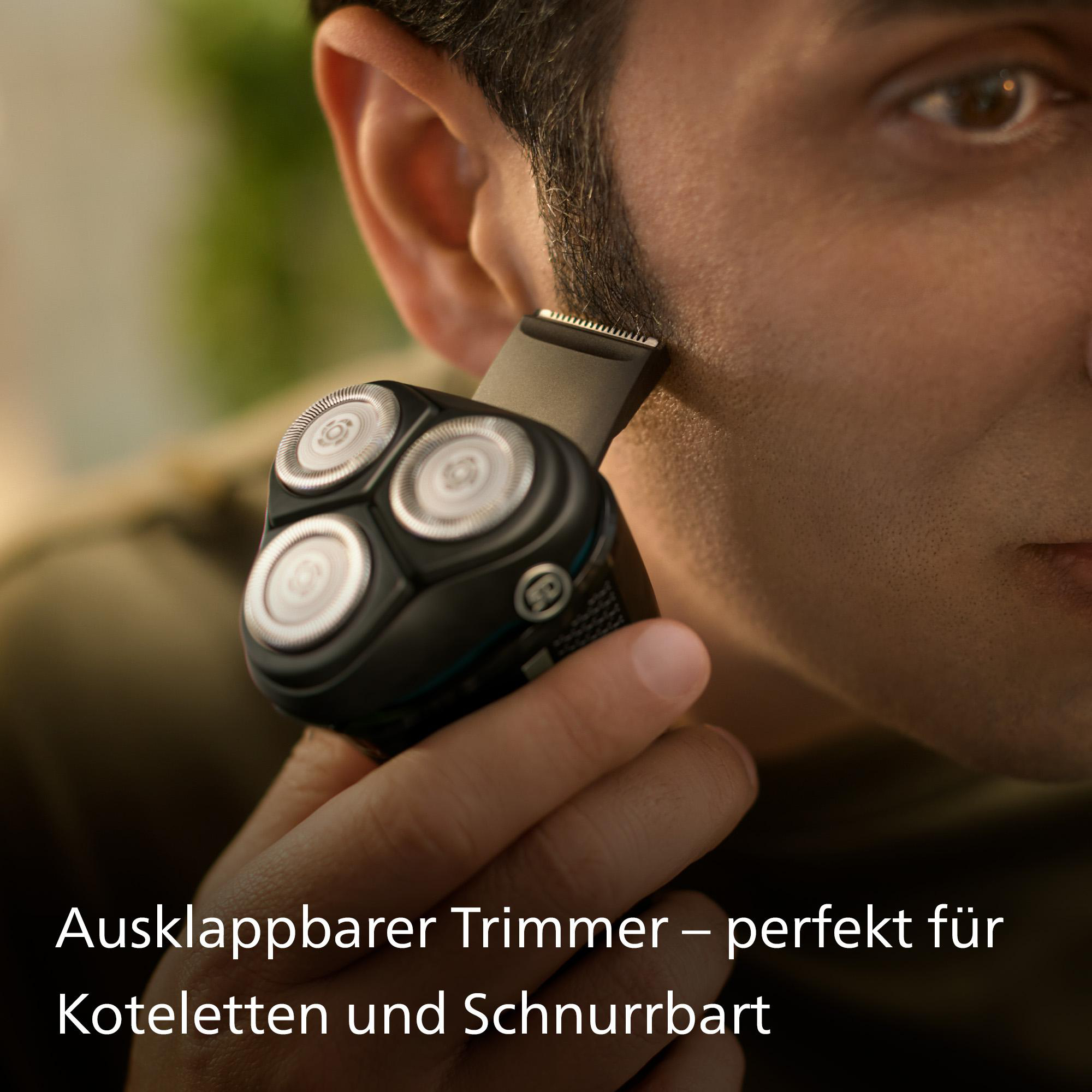 Mann rasiert sein Gesicht mit einem Trimmer. Nahaufnahme zeigt die Klingen des Trimmers.