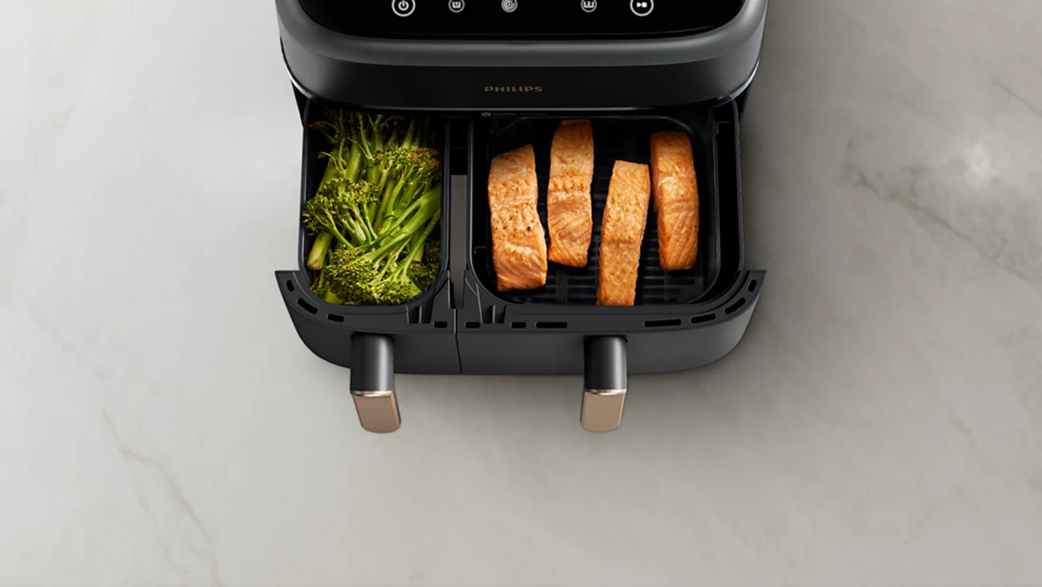 Fekete Philips air fryer étellel: brokkoli és lazacfilé.