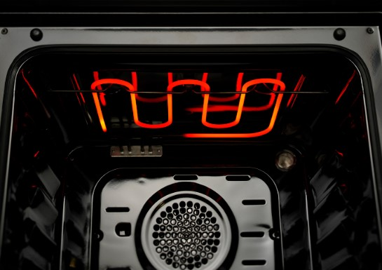 Oven interior with glowing red heating elements, viewed from the inside.