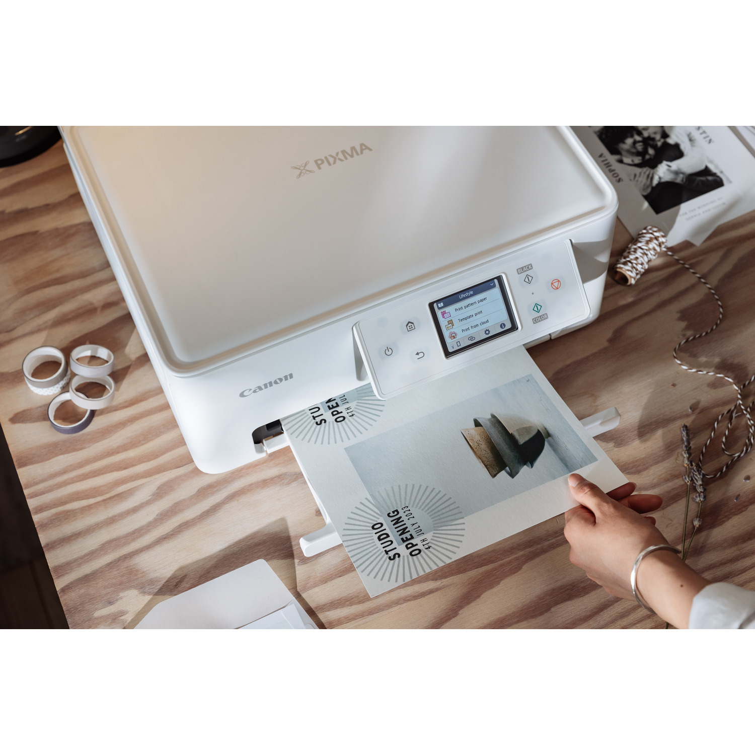 Canon printer die een papier afdrukt. Houten tafel achtergrond. Hand is zichtbaar.