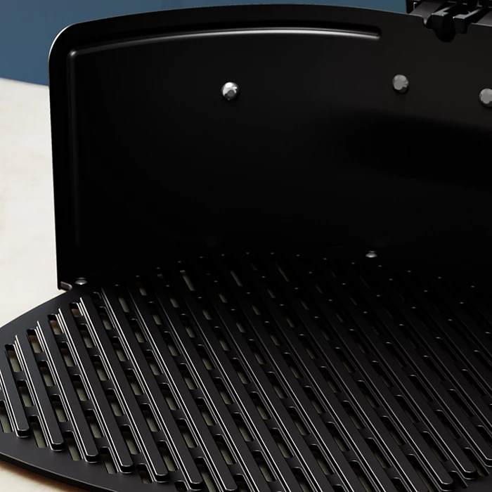 Zbliżenie na wnętrze czarnego grilla z widocznymi rusztami.