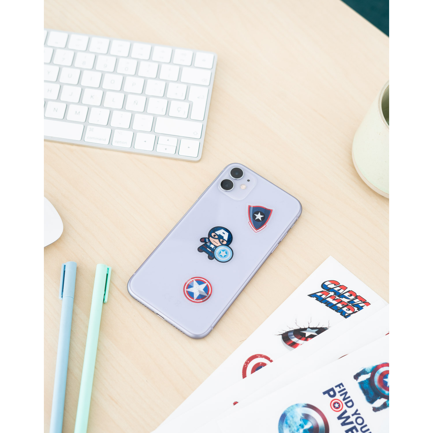 Una scrivania con un telefono con adesivi di Captain America, penne e una tastiera. Lo sfondo è sfocato.