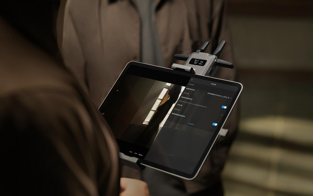 Eine Person hält ein Tablet und ein Telefon. Beide Geräte zeigen Informationen, wahrscheinlich für Videoproduktion.