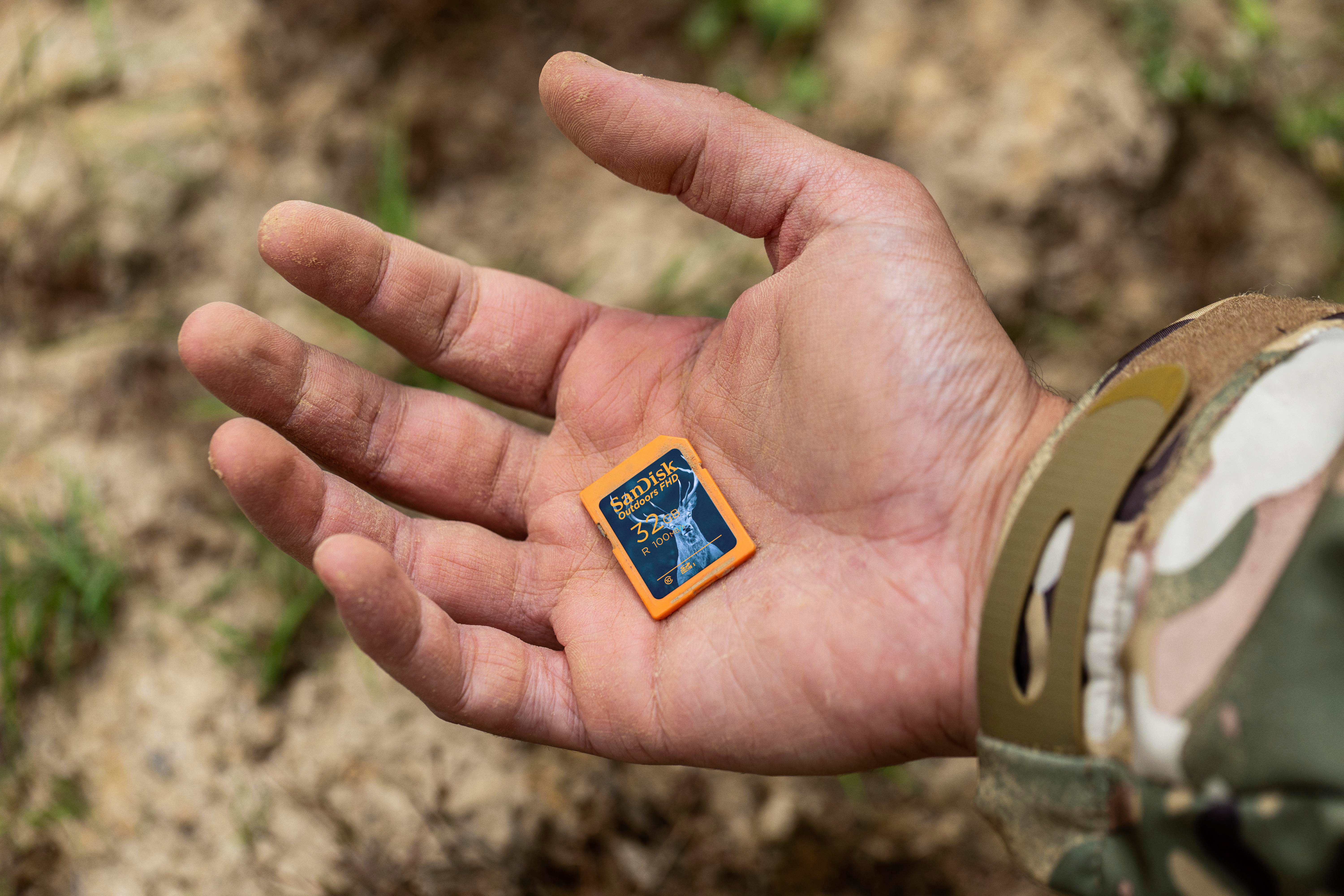 Hand hält SD-Karte. Orangefarbene Karte mit Logo auf verschwommenem Boden.