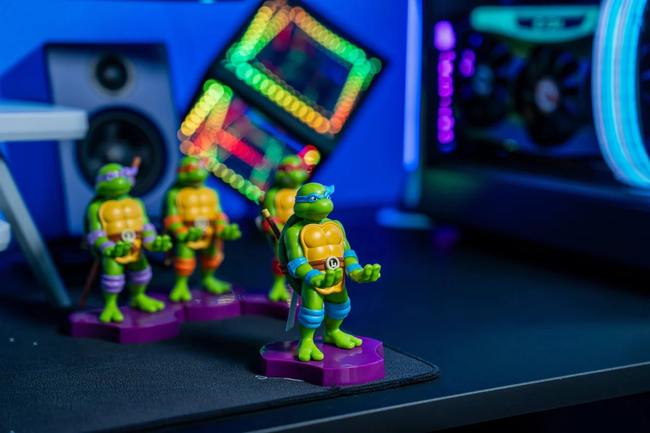 Figurines des Tortues Ninja sur un bureau, avec un PC de jeu en arrière-plan.