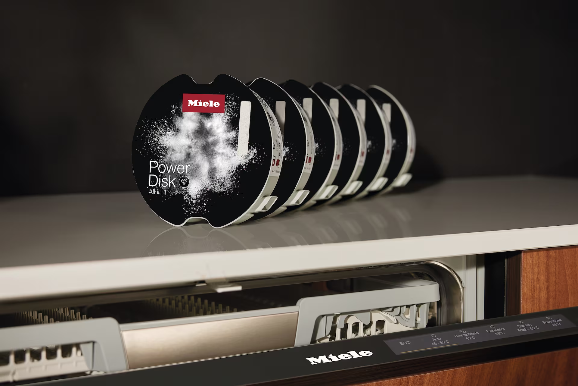 Egy sor Miele PowerDisk mosogatószer-csomag a konyhapulton.