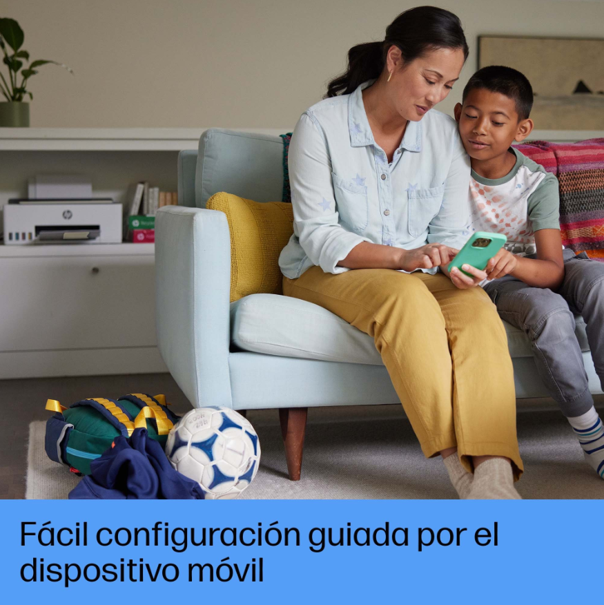 Una mujer y un niño sentados en un sofá mirando un teléfono móvil. Hay un balón de fútbol y una bolsa.