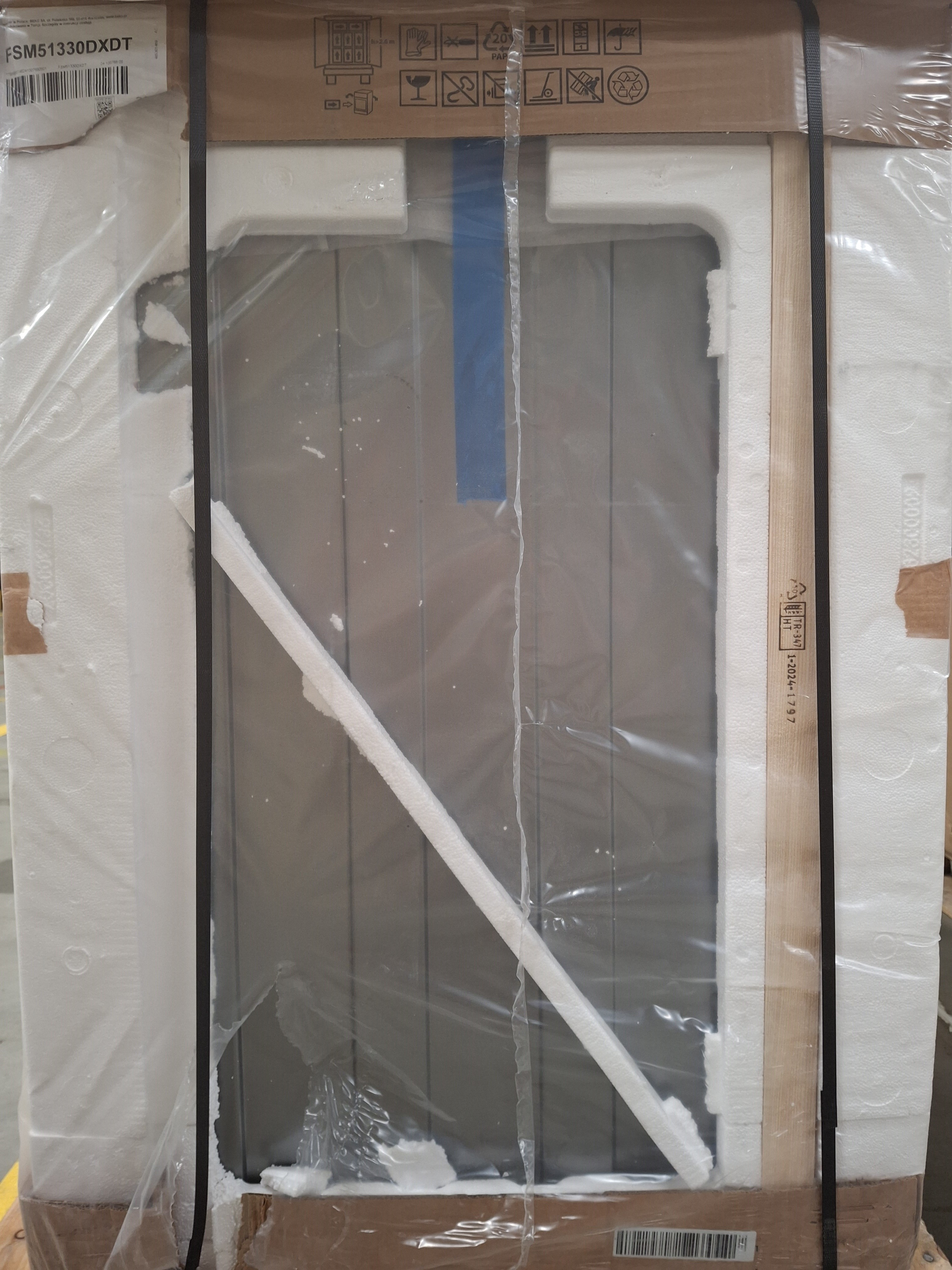 Kartónowe pudełko z zapakowanym przedmiotem w środku. Widoczna pianka ochronna i folia.