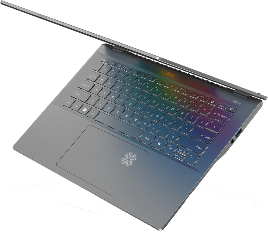 Nyitott fedelű laptop, szivárványszínnel világító billentyűzet, ferdén egy felületen.