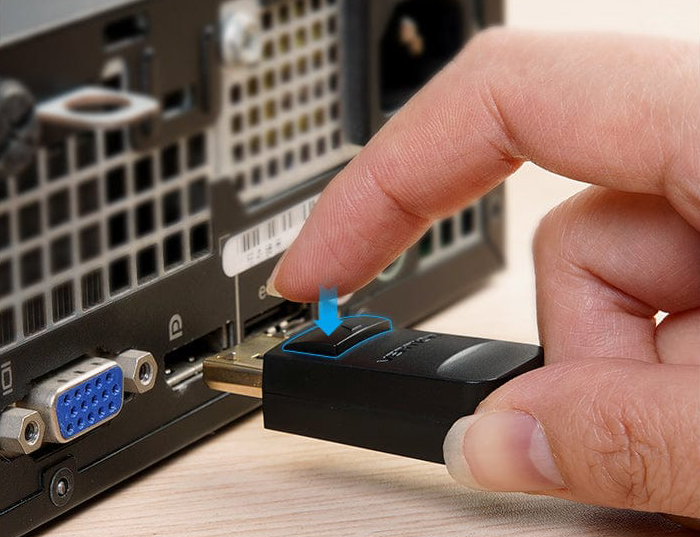 Egy kéz fekete HDMI adaptert dug a számítógép portjába. Kék nyíl a csatlakozásra mutat.