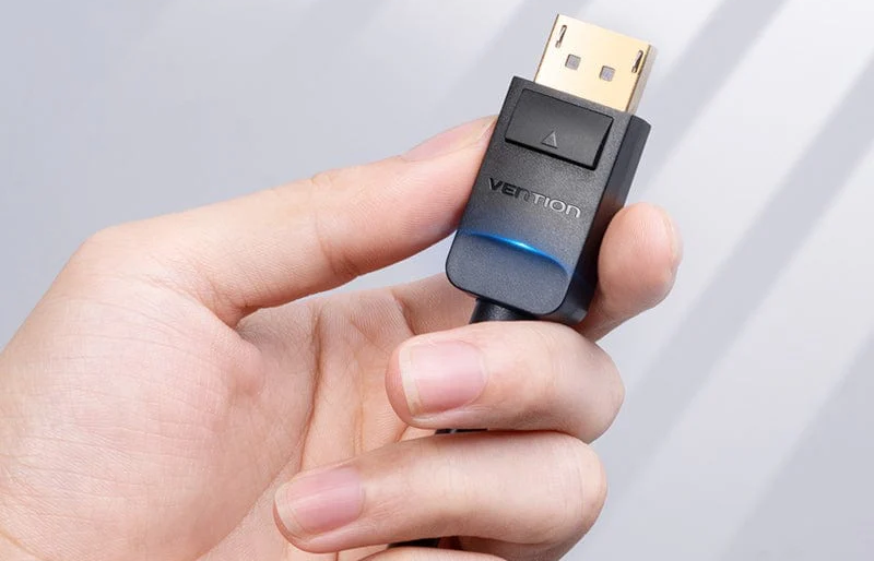 Egy személy keze egy fekete DisplayPort kábelt tart a Vention logóval és kék fénnyel.