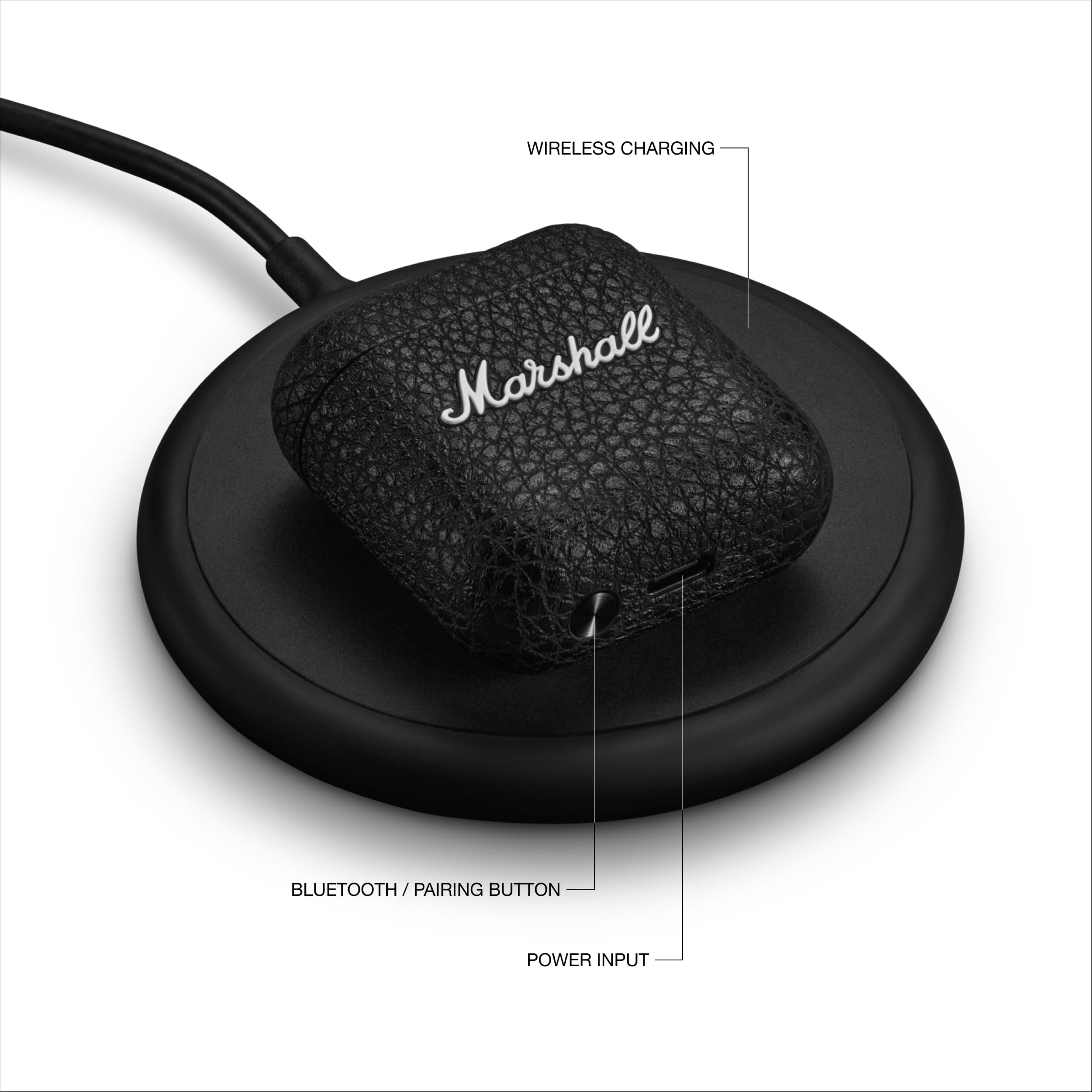 Marshall logosu bulunan siyah kablosuz şarj kutusu, siyah bir şarj pedinde, metin açıklamalarıyla.