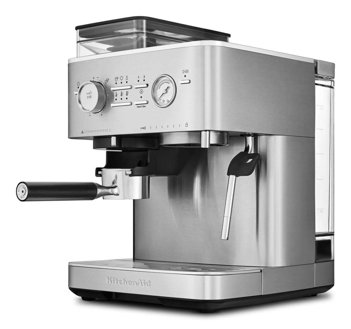 Eine silberne Espressomaschine mit schwarzem Griff und verschiedenen Bedienelementen. Sie steht auf einer Theke.