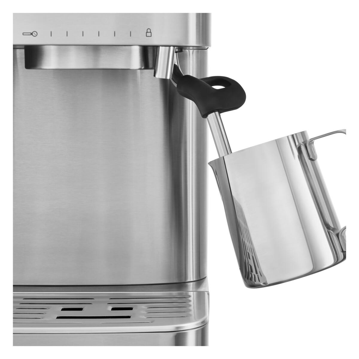 Nahaufnahme einer silbernen Espressomaschine mit Aufschäumdüse und Kanne.