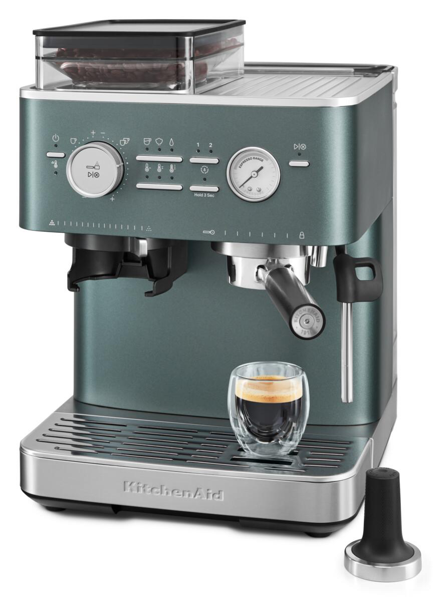 Eine türkisfarbene KitchenAid Espressomaschine mit einem Glas Espresso und einem schwarzen Tamper.