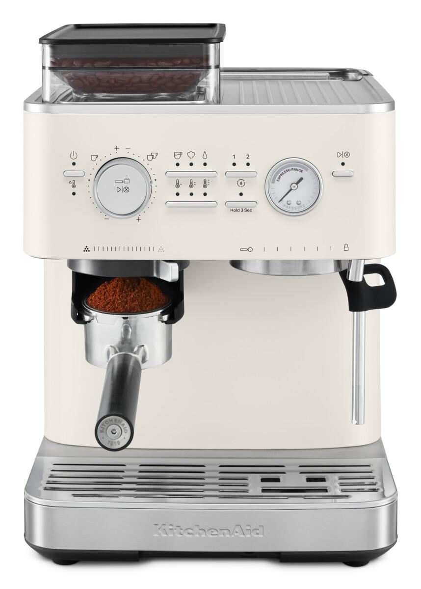 Eine cremefarbene Espressomaschine mit einem Kaffeebohnenbehälter. Ein Siebträger hält Kaffeepulver.
