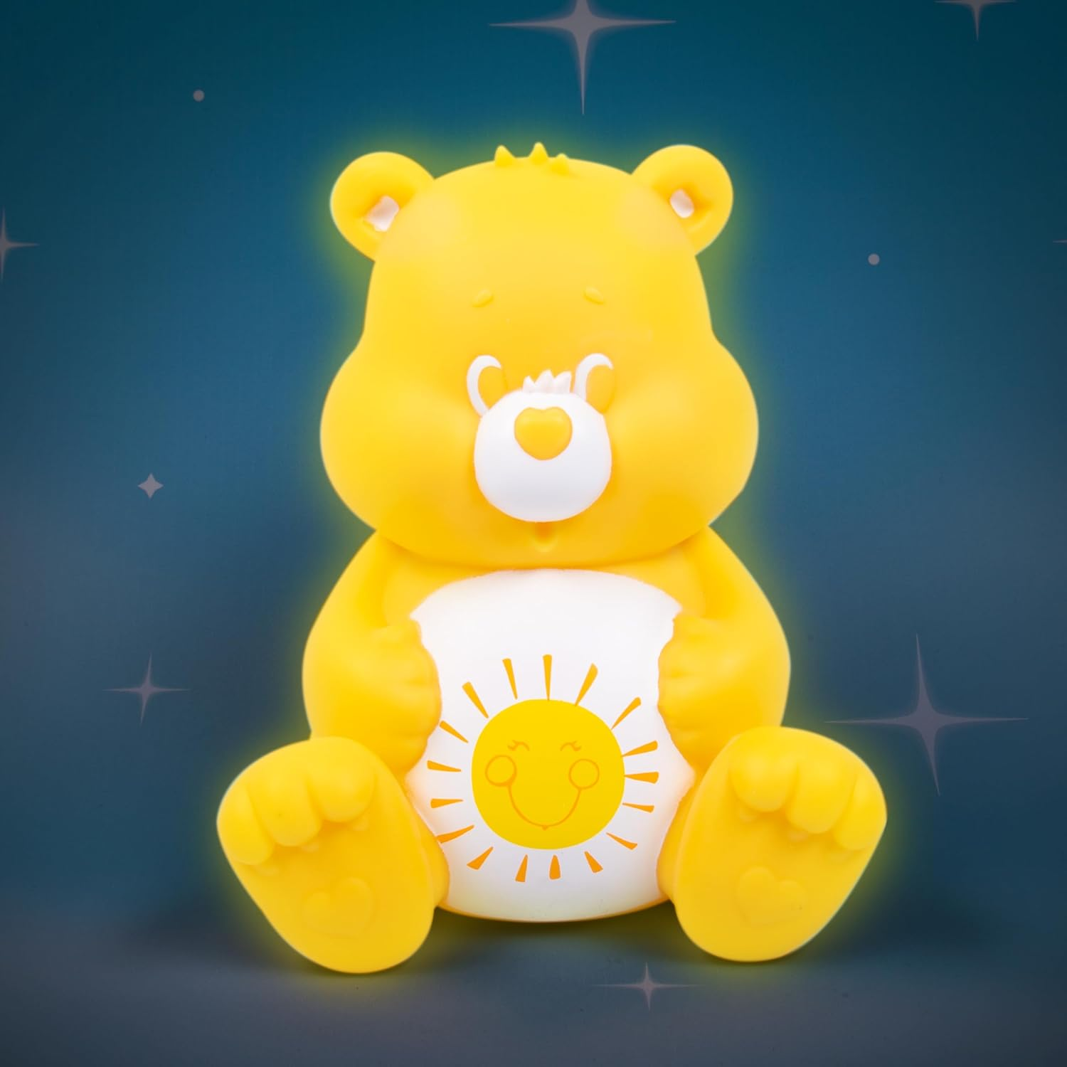 Figurine jaune Care Bear avec soleil sur le ventre, brillant sur fond bleu foncé.
