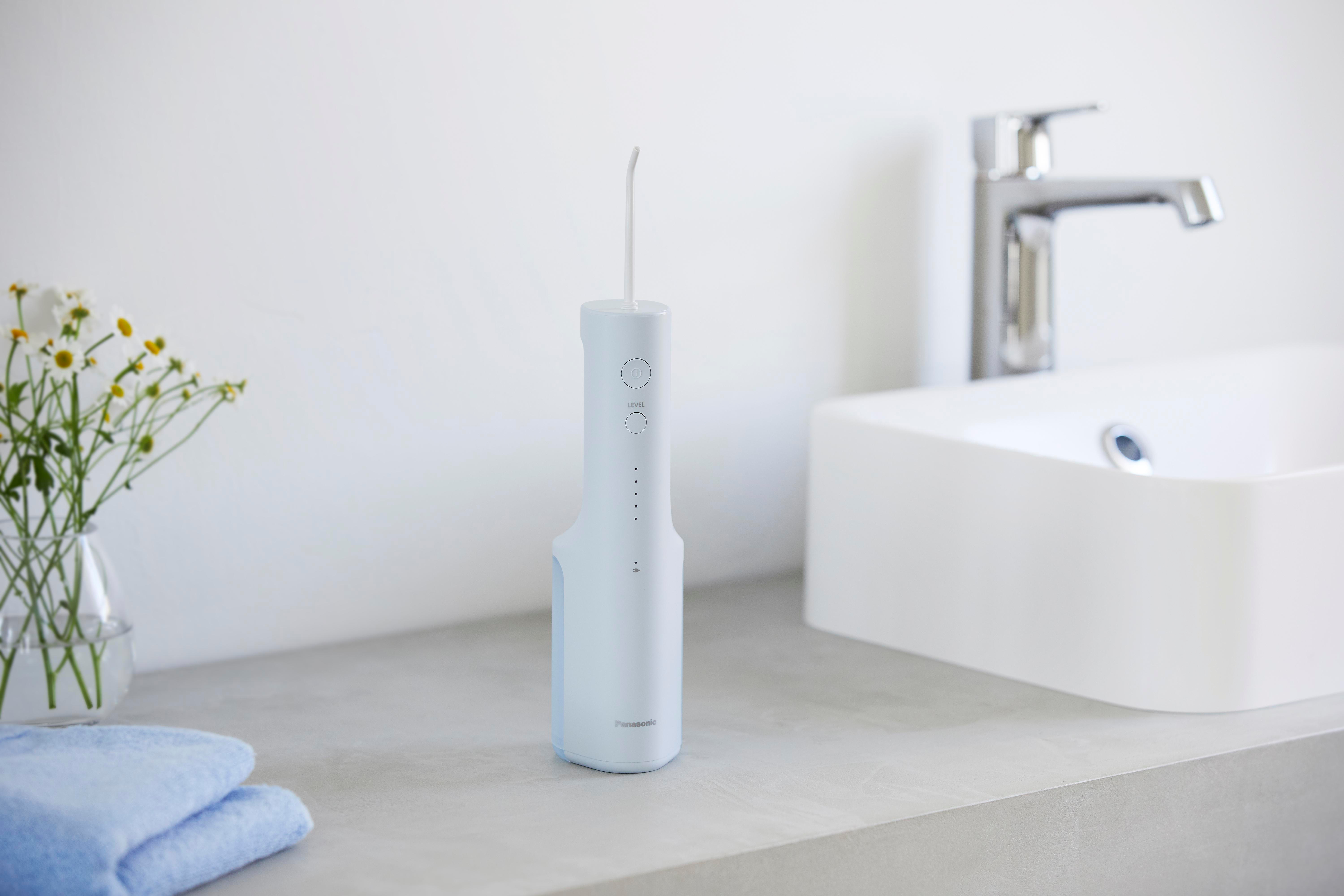 Weißer Wasserflosser auf einer Arbeitsplatte. Eine Vase mit Blumen und ein Handtuch sind ebenfalls vorhanden.