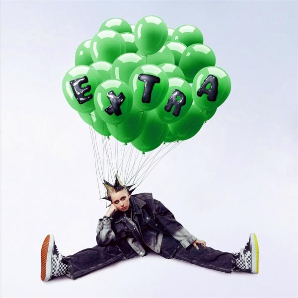 Person mit grünen Ballons mit der Aufschrift EXTRA, die am Boden sitzt.