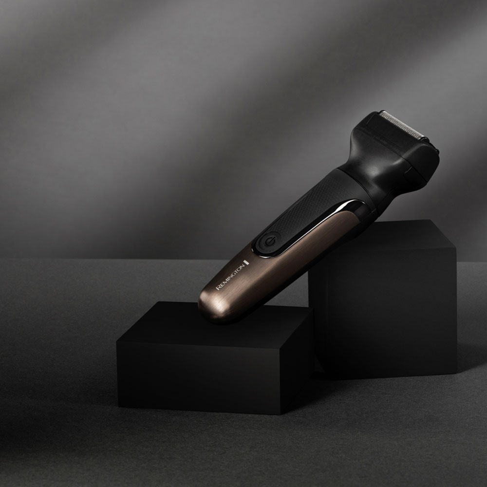 Siyah ve bronz bir Remington tıraş makinesi, siyah küpler üzerinde, gri bir arka plan ile.
