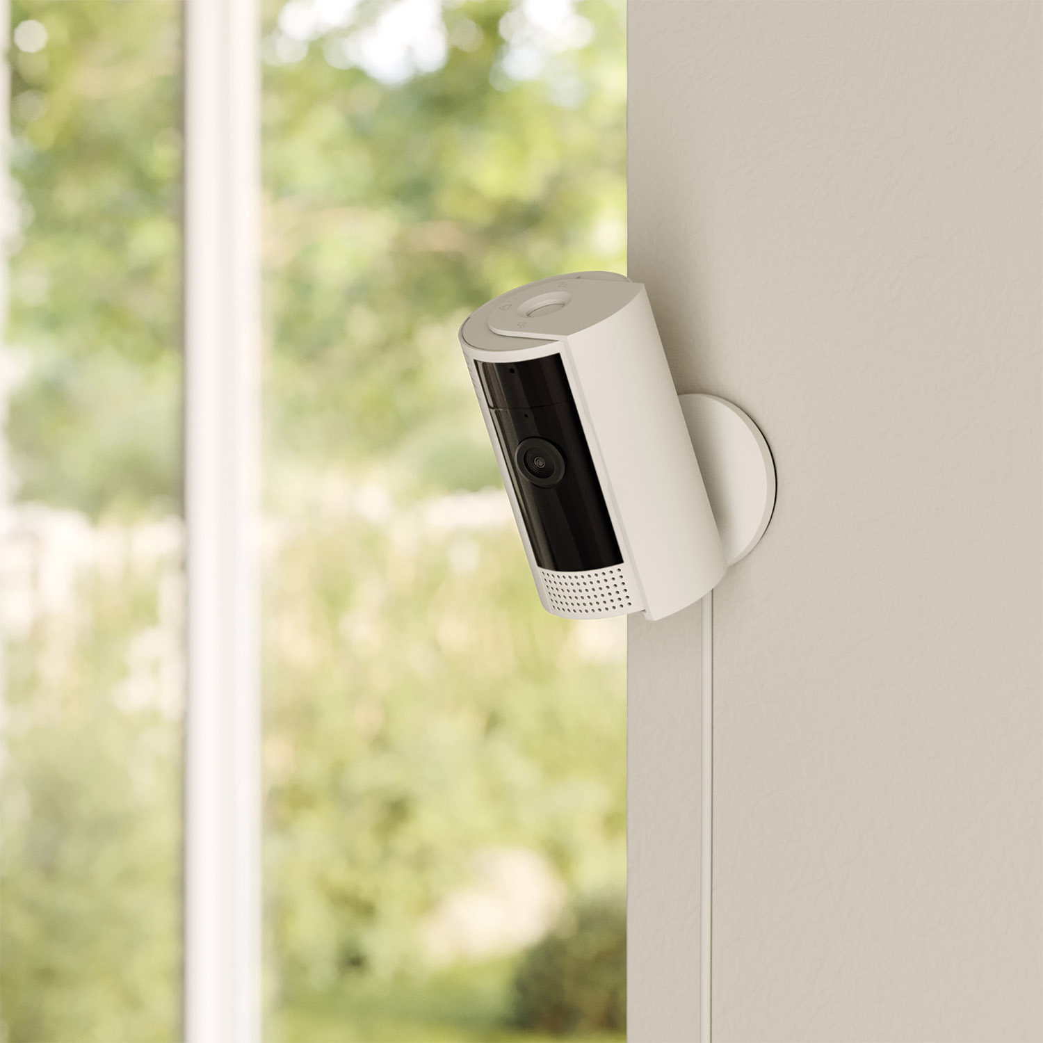 Una telecamera di sicurezza Ring bianca montata su un muro, rivolta verso una finestra.