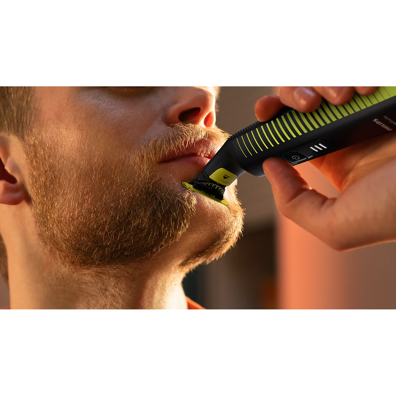 Persona che usa un tagliabarba Philips nero e verde sul viso di un uomo.