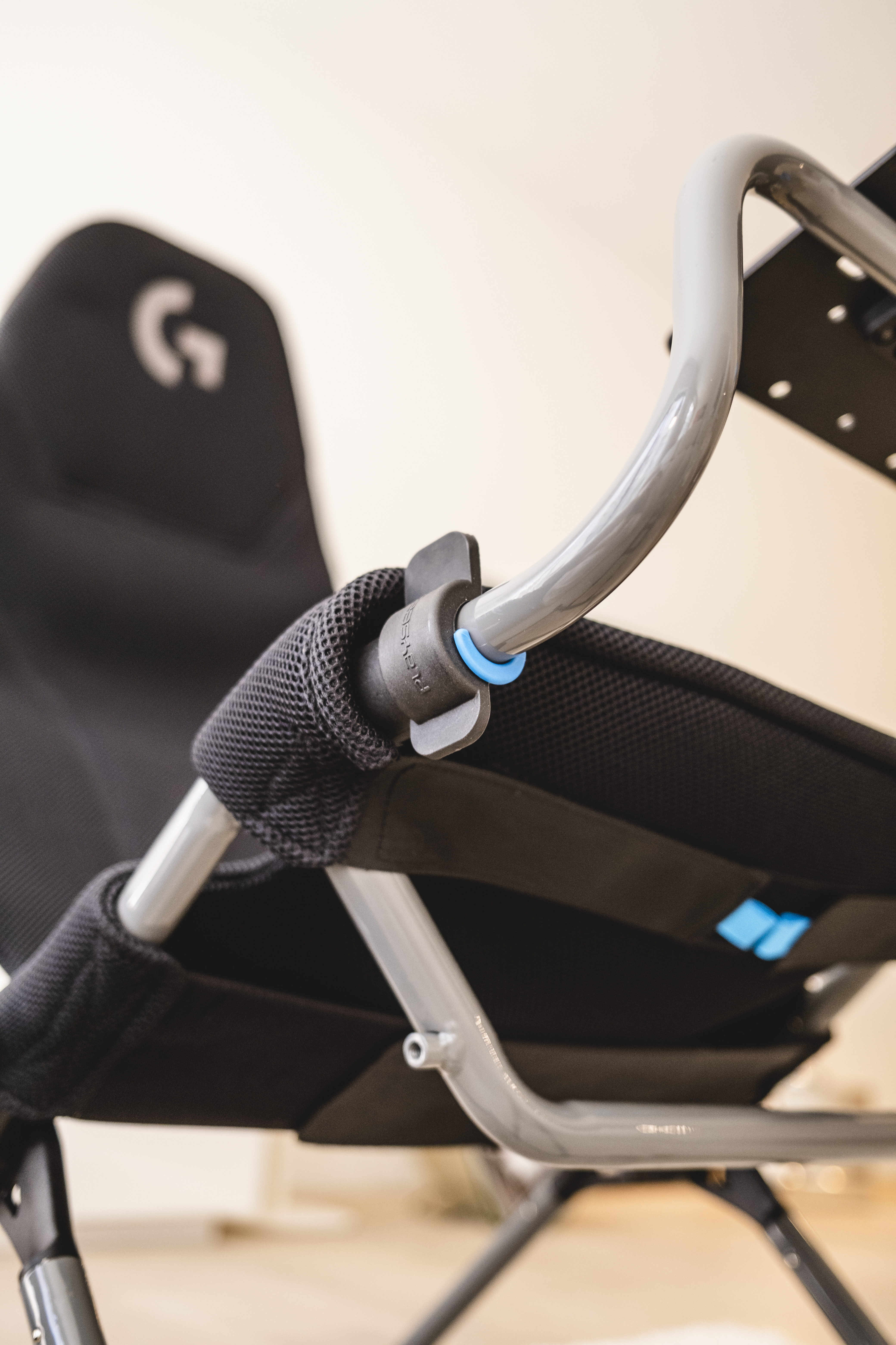 Nahaufnahme eines schwarzen Logitech Gaming-Stuhls mit Armlehne und blauem Ring.