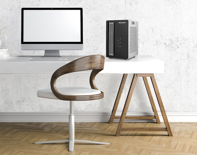 Monitor komputerowy i oczyszczacz powietrza Honeywell znajdują się na białym biurku.