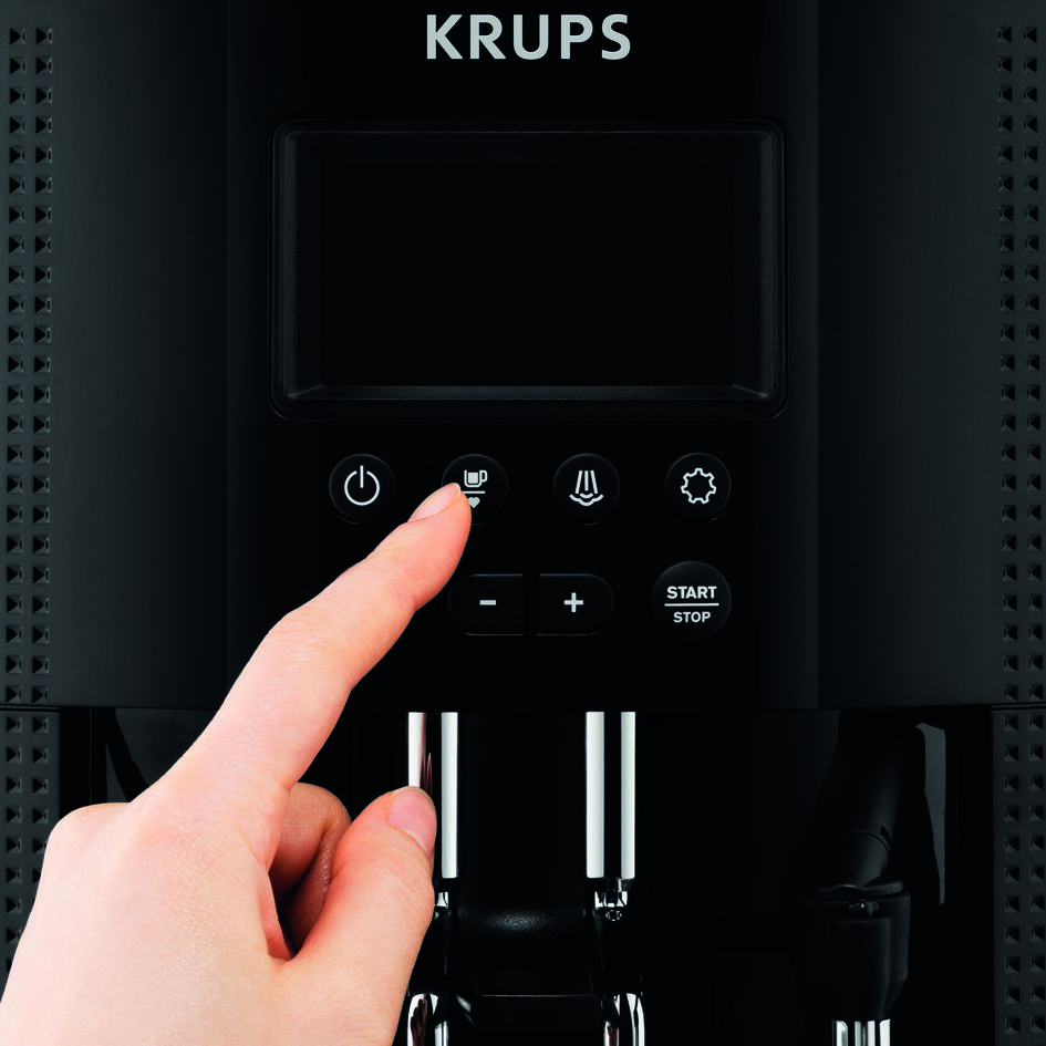 Gros plan sur le panneau de commande d'une cafetière Krups noire. Un doigt appuie sur un bouton. Le fond est noir.