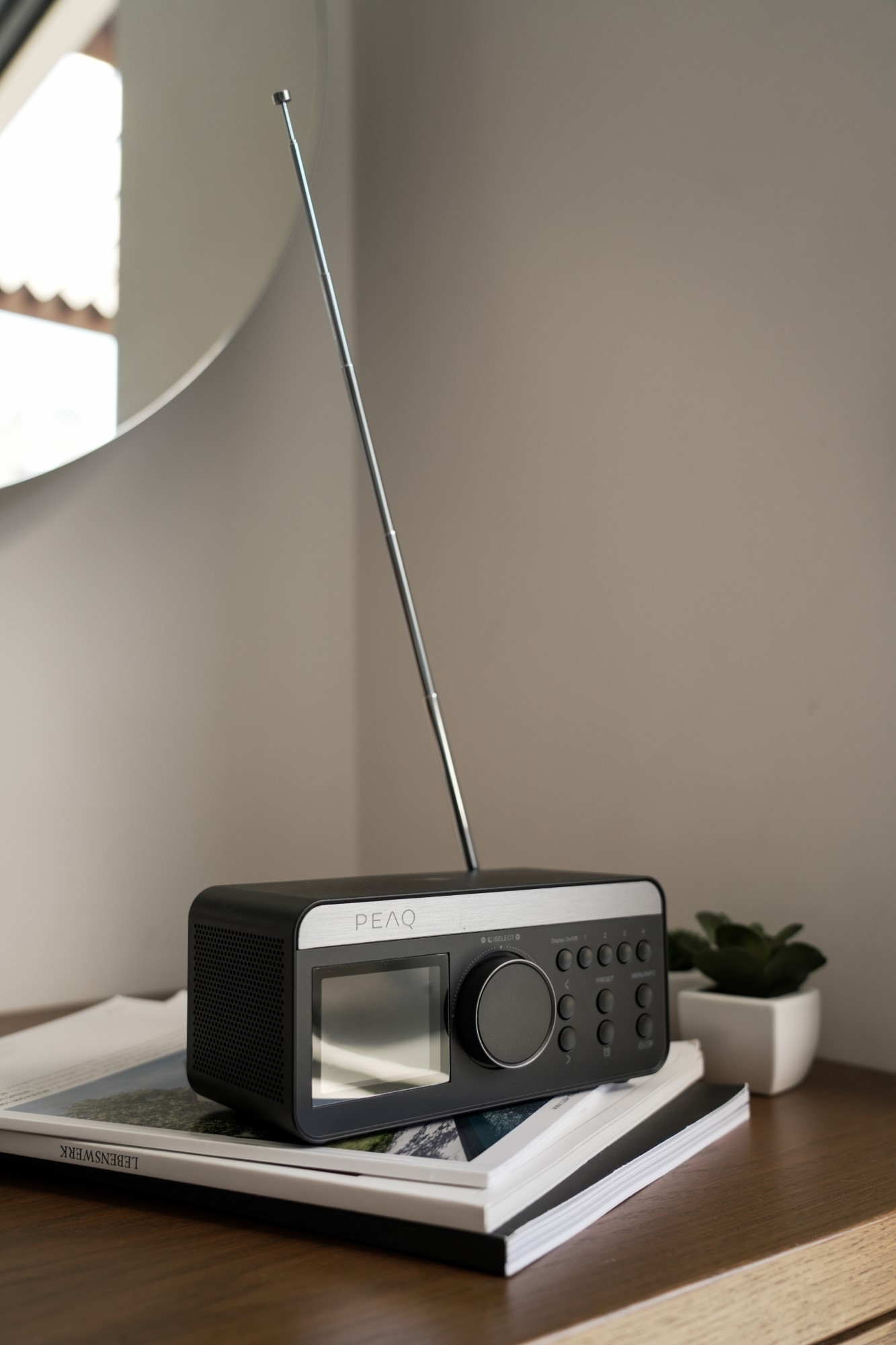 Czarno-srebrne radio z anteną na drewnianej powierzchni obok małej rośliny.