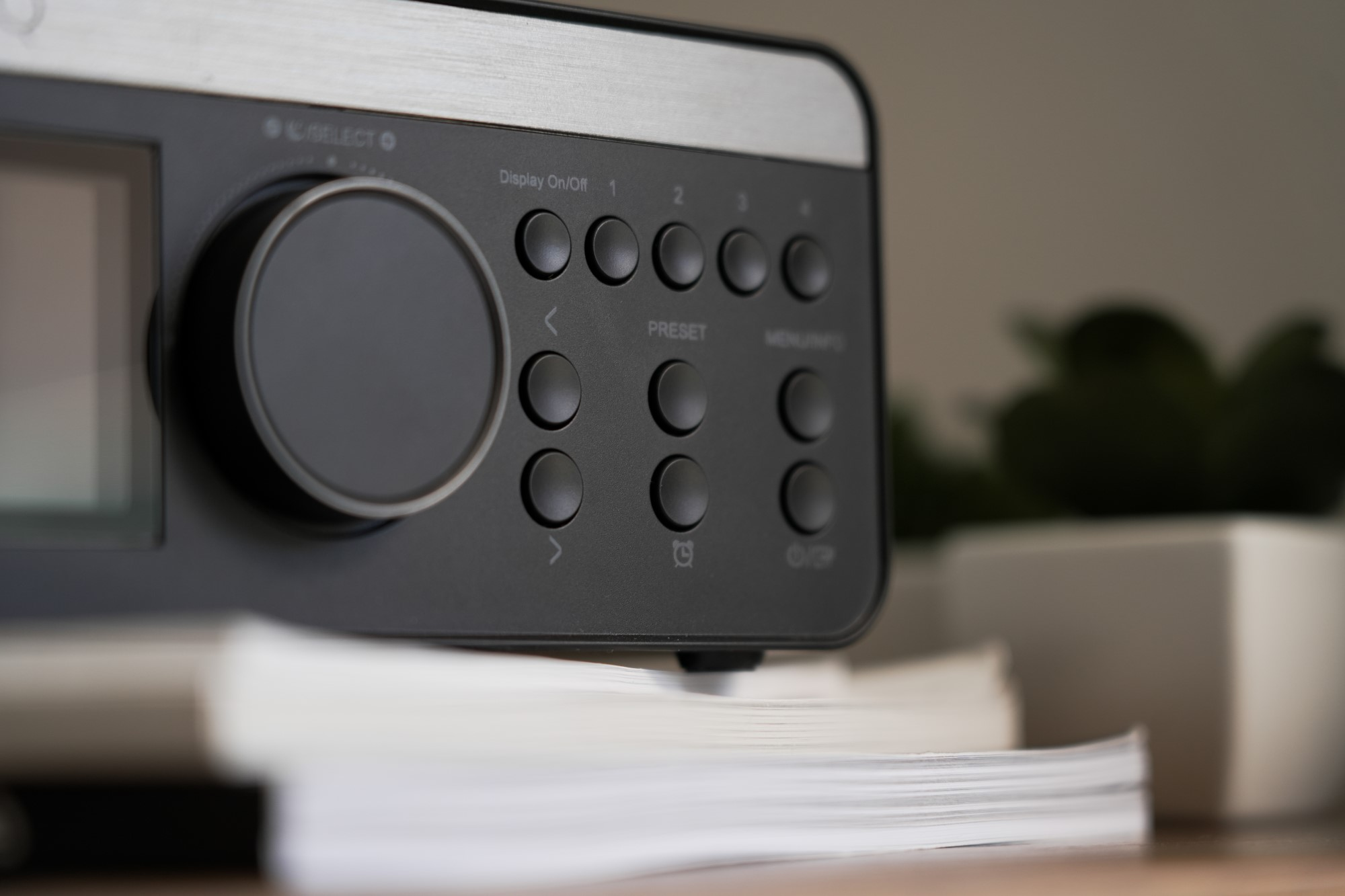 Zbliżenie czarnego radia z przyciskami i wyświetlaczem. Na pierwszym planie znajdują się książki.