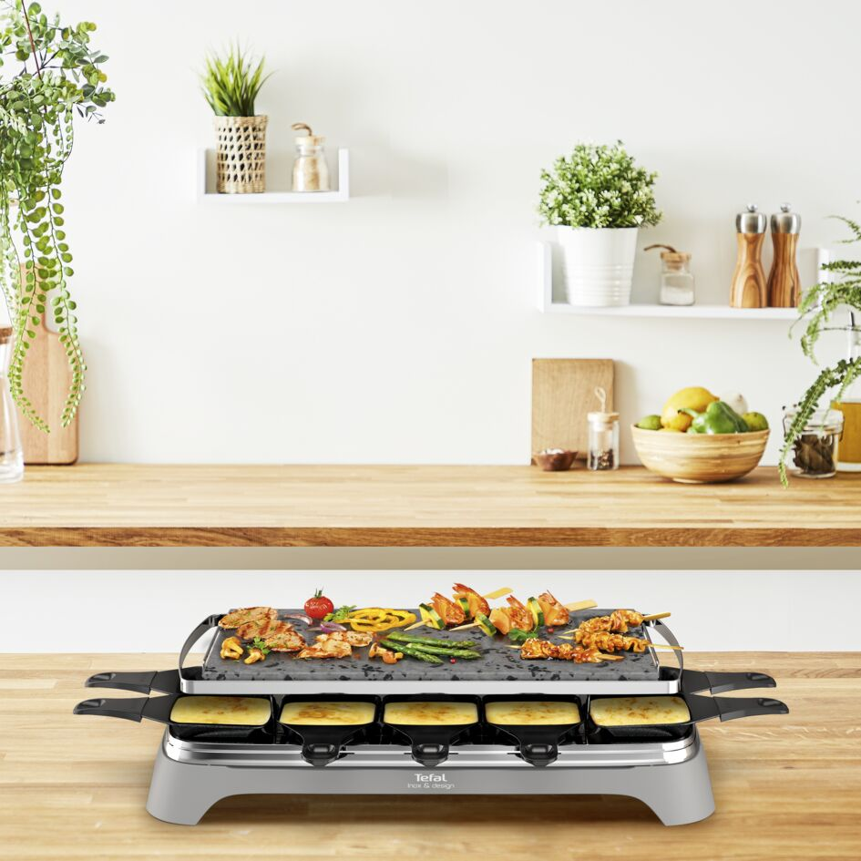 Raclette grill met eten erop en kaaspan onder.