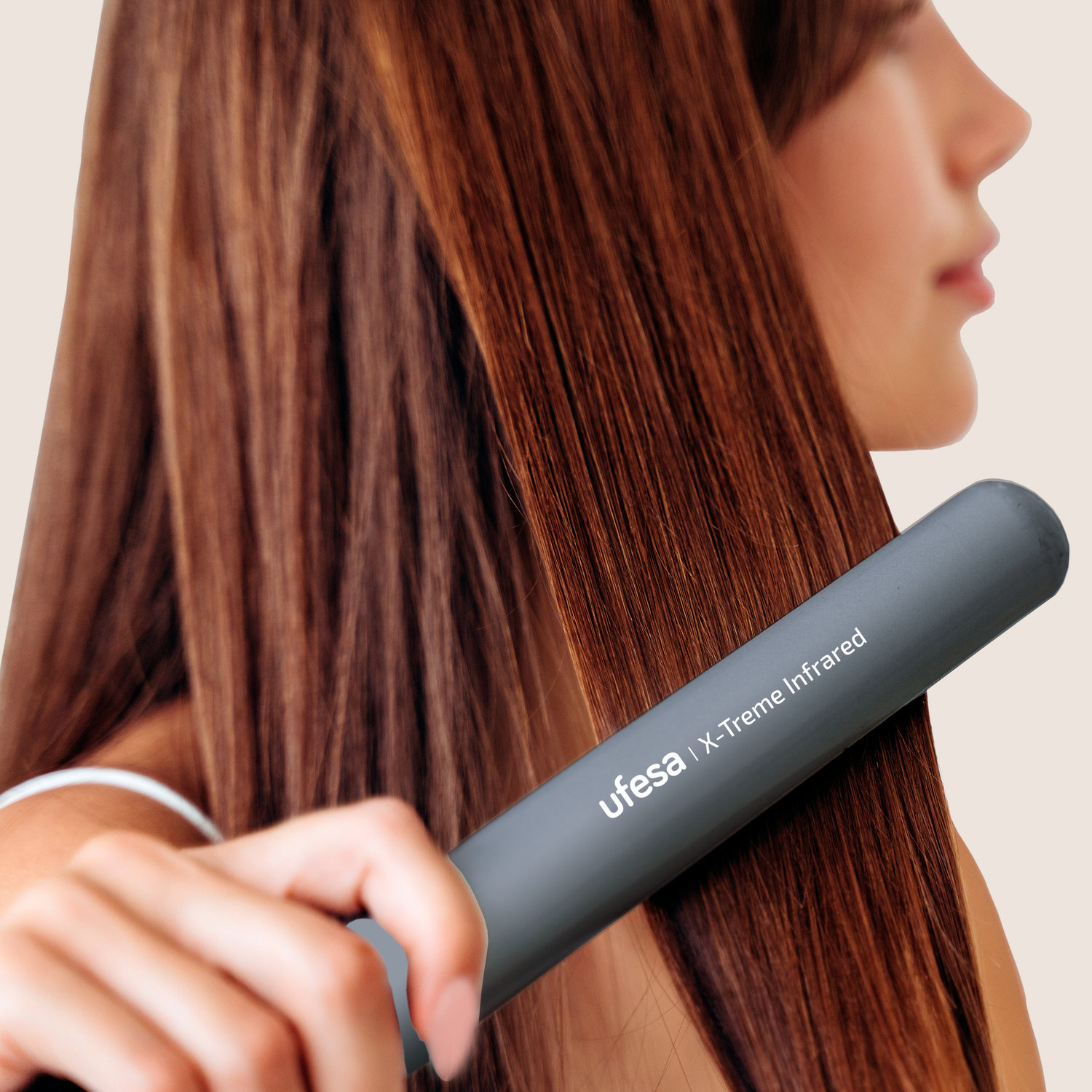 Una mujer usando una plancha gris en su cabello.