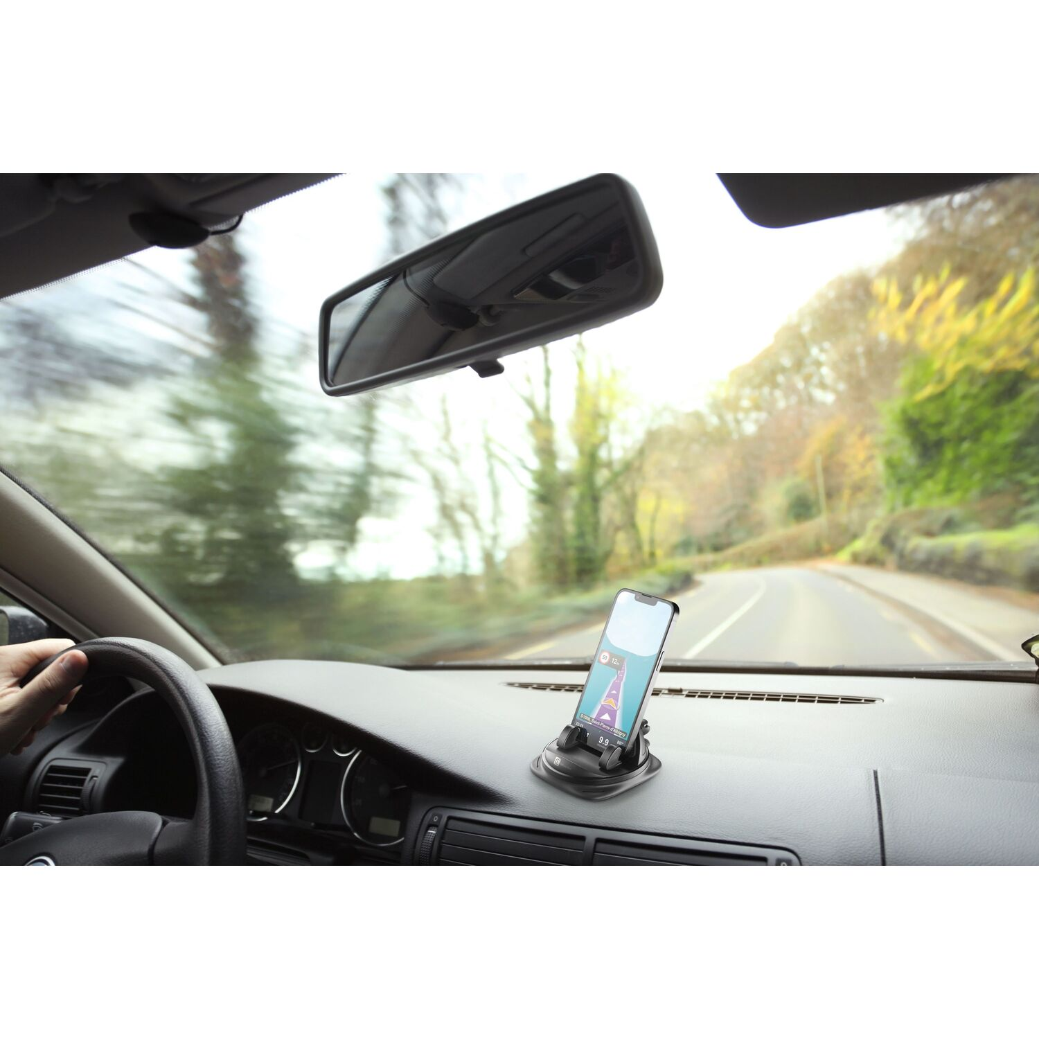 A car interior with a phone mounted on the dashboard, showing a navigation app.