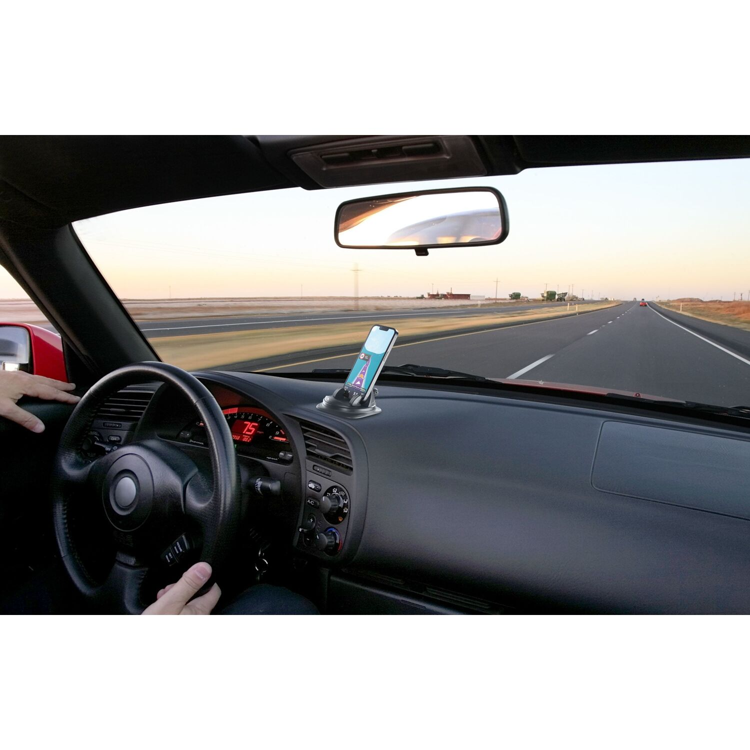 Car interior with a phone mounted on the dashboard, driving on a highway.