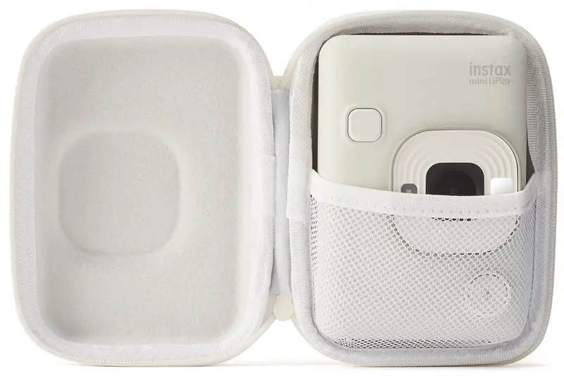 Biały aparat w białym etui z siatkową kieszenią, otwarty na białej powierzchni.